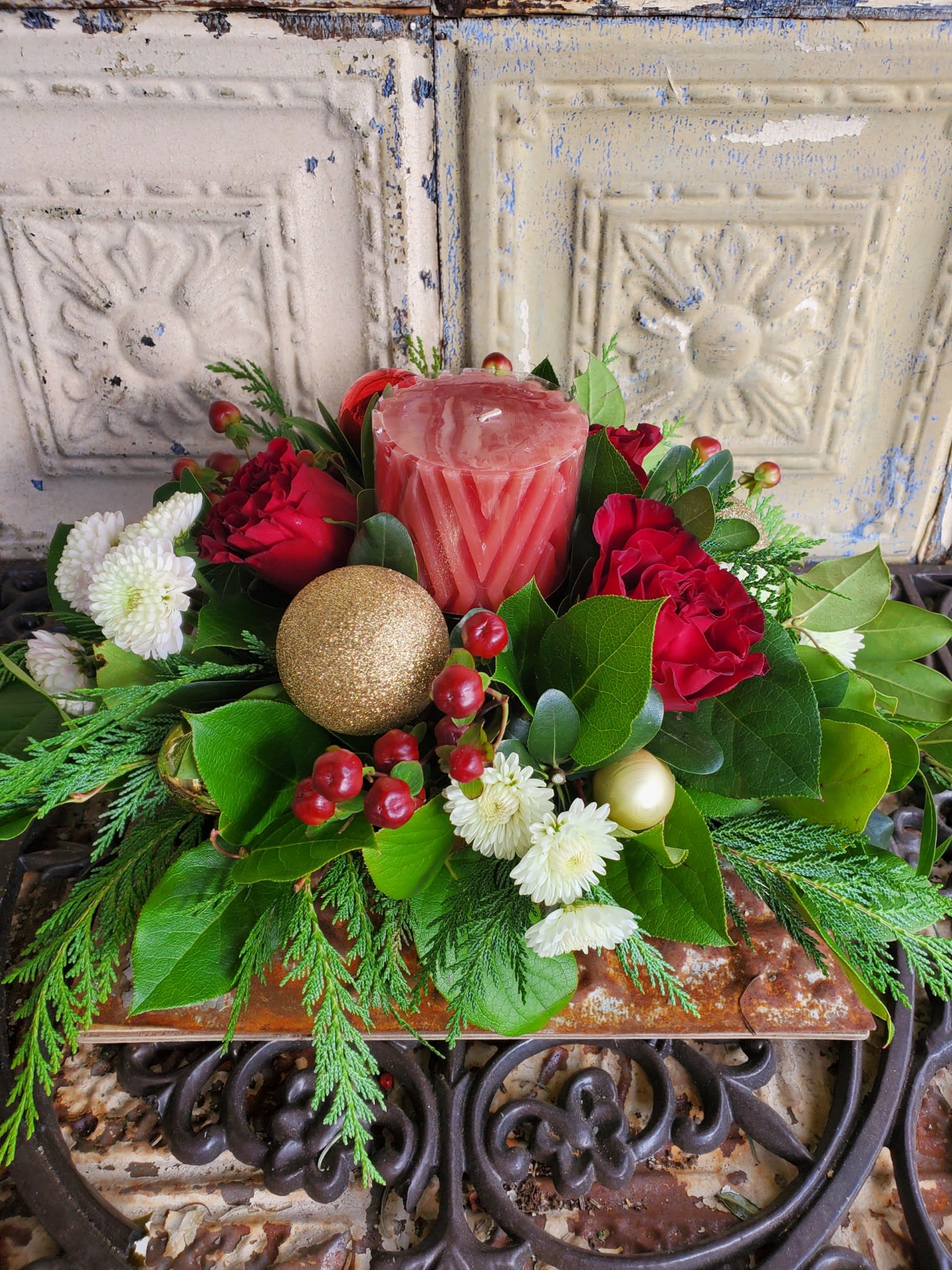 Margaret Thatcher - A perfect holiday centerpiece with cedar, roses, button poms, hypericum berries, assorted Christmas ornaments, and a pillar candle. 