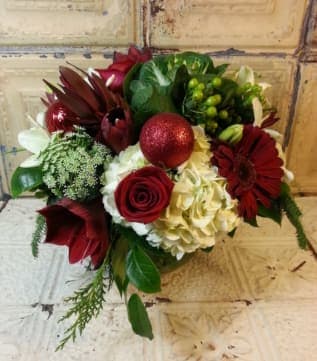 Clara Barton - Spread holiday cheer with this arrangement of hydrangeas, lilies, roses, gerbera daisies, amaryllis, Queen Anne's lace, hypericum berries, kale, protea, mixed Christmas greens, decorative Christmas ornaments. 