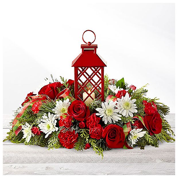 FTD Celebrate The Seasons - A stylish way to deck your halls this holiday season, this stunning centerpiece offers Christmas beauty to help you gather your loved ones together during this treasured time. Red roses, carnations , and mini carnations are beautifully arranged amongst white chrysanthemums, and an assortment of holiday greens all surrounding an attractive red lantern with a lattice pattern housing a single white votive candle. A great gift for friends and family, but also an wonderful way to decorate your own holiday table! Lantern is approx 4 1/4&quot; sq. x 9&quot;H.