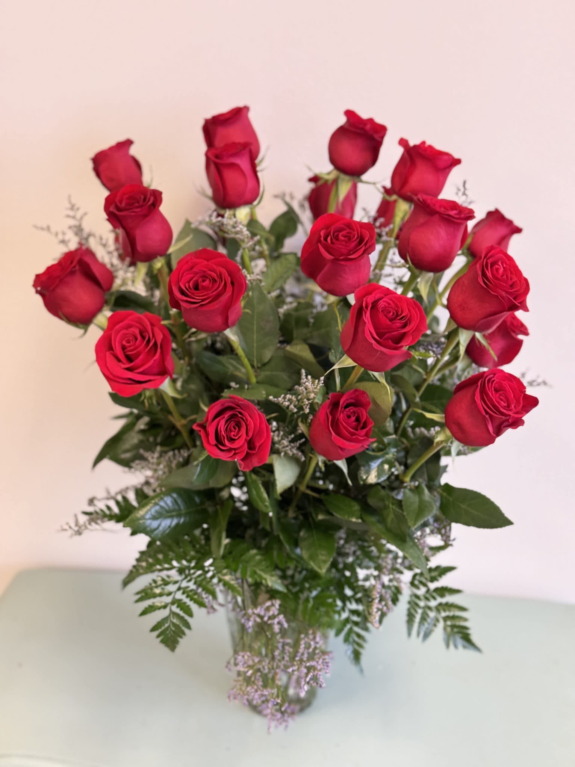 Isn’t It Romantic (2 Dozen Roses) - Explore your love with this impressive display of two dozen long stem premium imported red roses arranged in a clear glass vase.