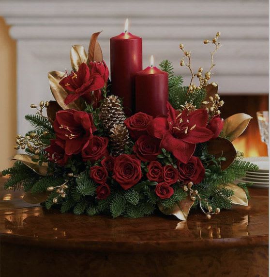 Crimson Candle Elegance - luxurious holiday centerpiece featuring deep red amaryllis and roses, accented with golden leaves, pinecones, and lush evergreens. Two rich burgundy candles add a warm, festive glow — perfect for Christmas dinners or elegant winter gatherings.