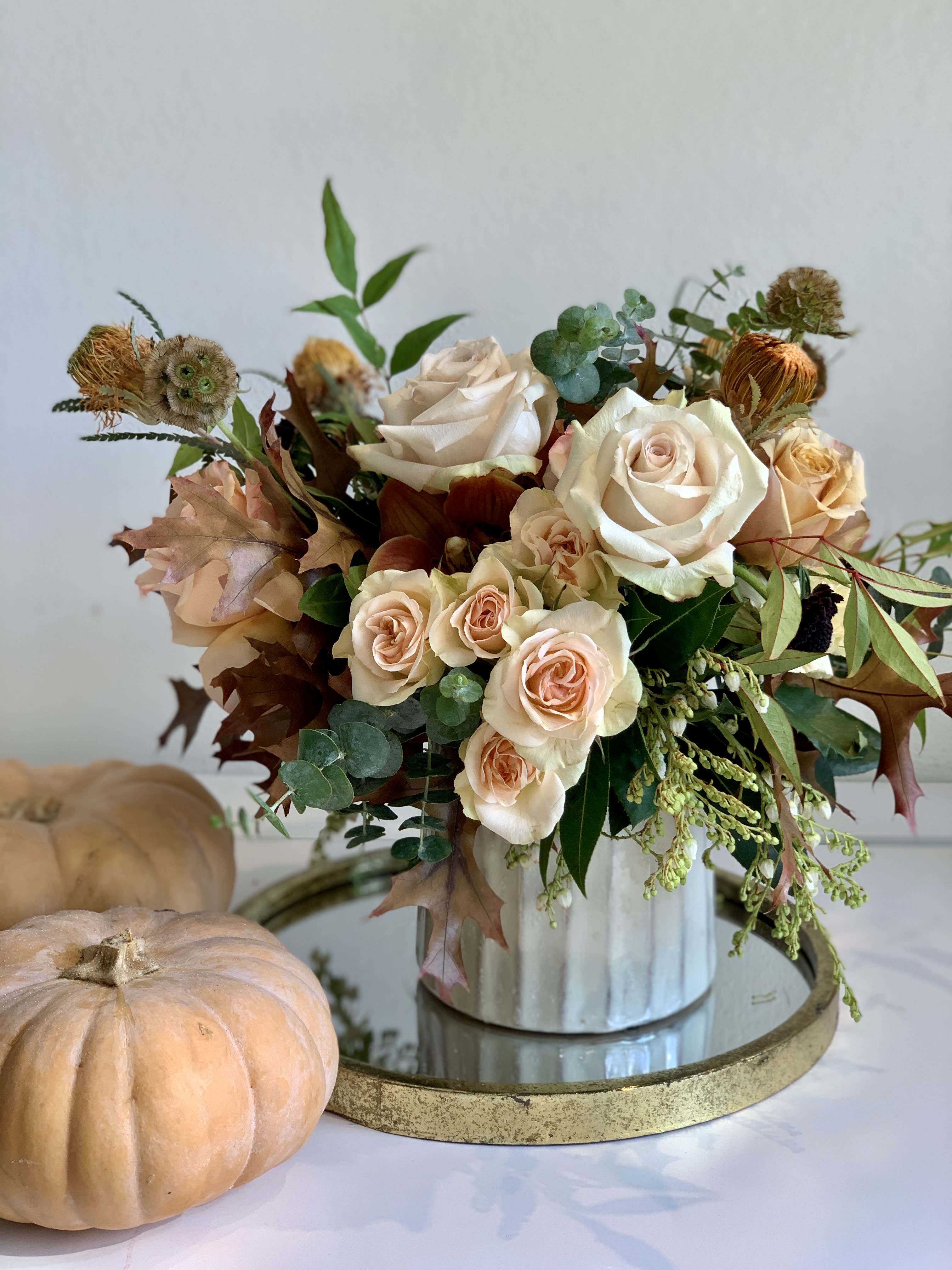 Autumn Catalina - A soft coastal-inspired fall arrangement featuring blush, cream, and caramel tones designed in a ceramic vessel. Autumn Catalina captures the feeling of warm light and sea air with an elegant, textural mix of roses, fall foliage, and golden accents. 