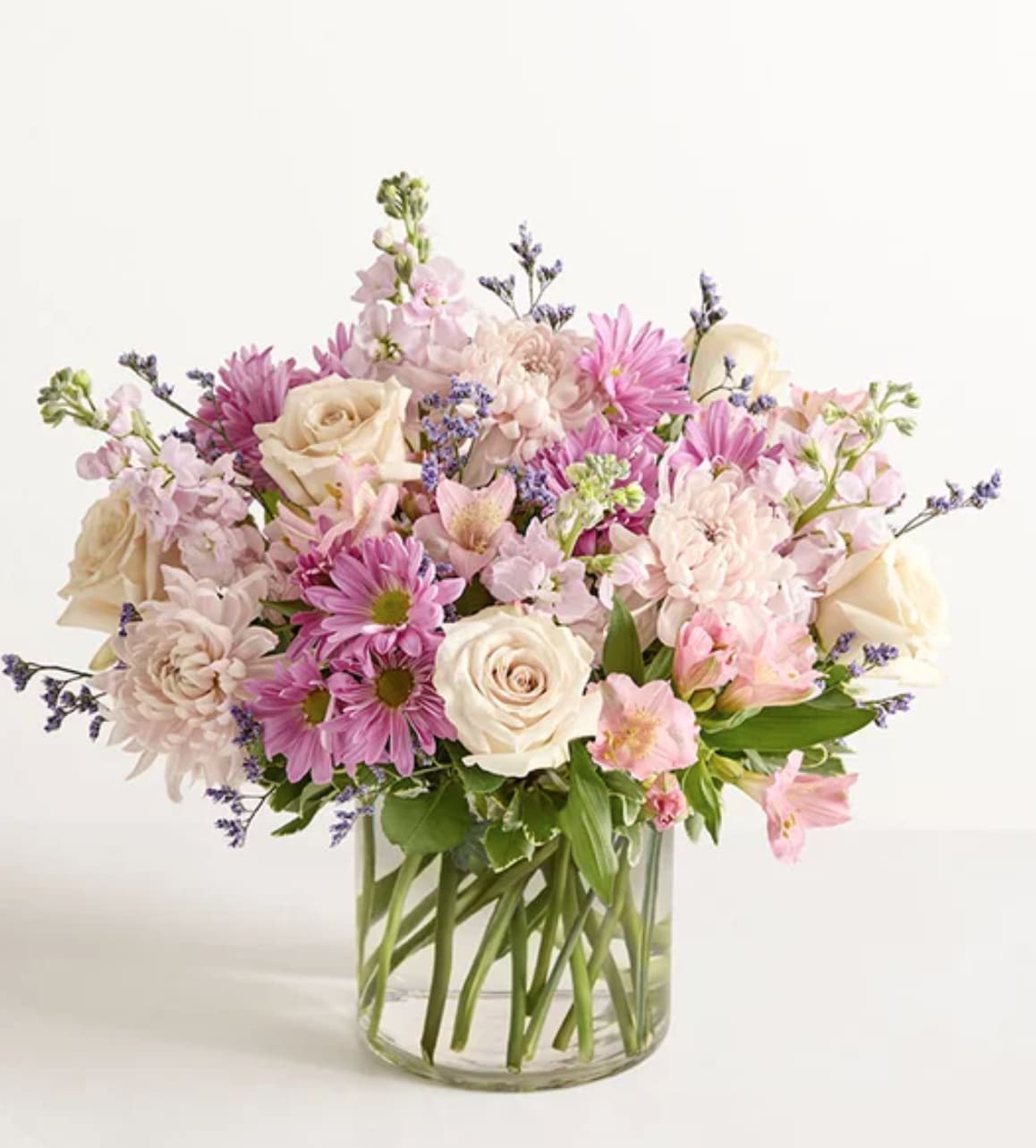 Blush Breeze - A blush and lavender flower arrangement with daisy, roses and gerbers in a glass vase with greenery!