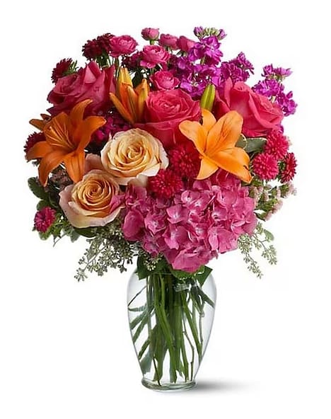 Joy Forever  - Mom = Wow! That’s what they’ll say when this explosion of color arrives at the front door. They’ll love the flowers, the clear glass vase – and you for having such exciting taste. A win-win for everybody! The vibrant bouquet includes pink hydrangea, peach and hot pink roses, orange Asiatic lilies, purple stock, hot pink Matsumoto asters, peach statice, and hot pink spray roses accented with fresh greenery. The flowers are delivered in a contemporary clear glass vase. 