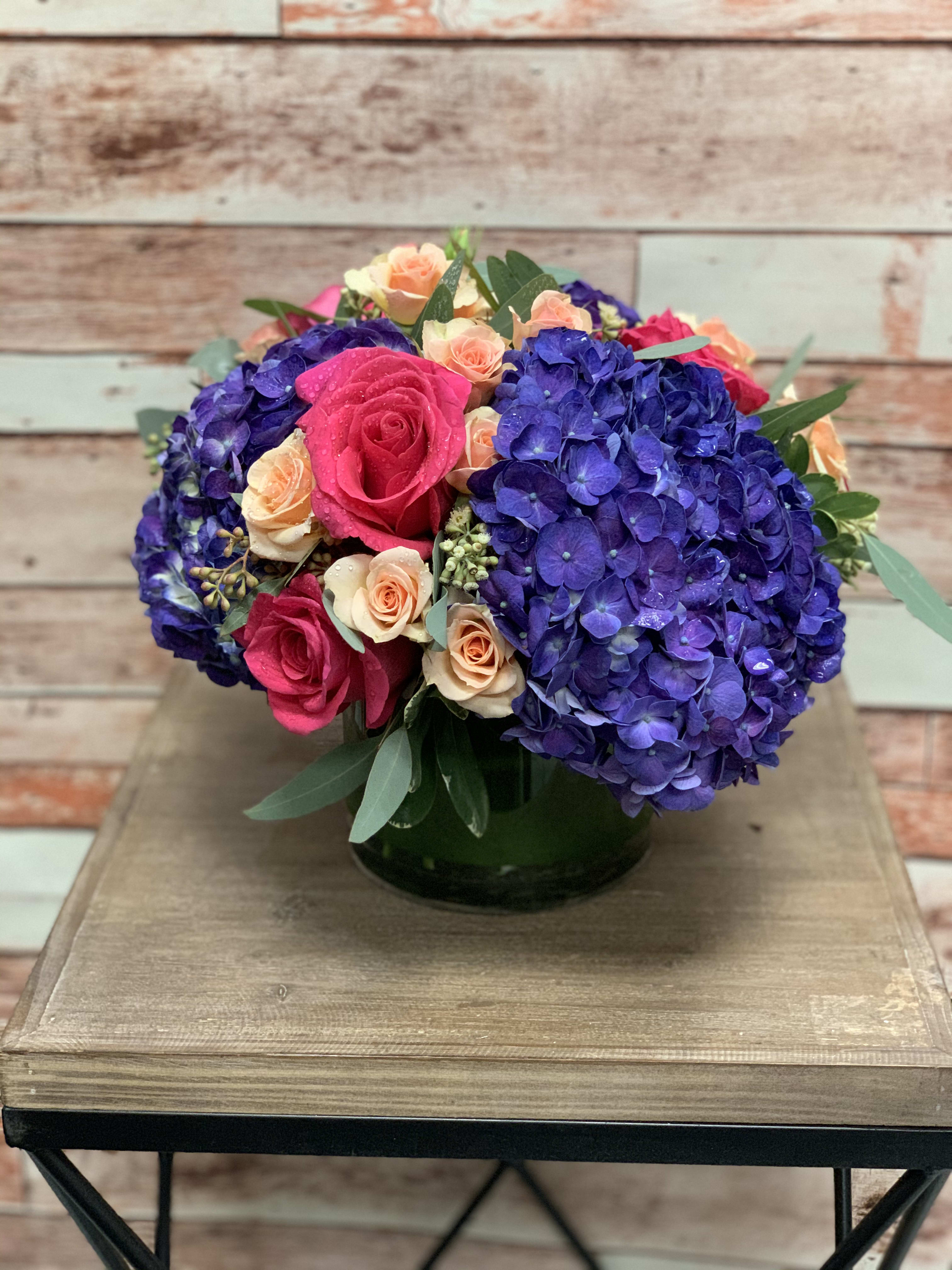 Midsummer Dream  - Deep purple hydrangeas and light colored roses make up this striking arrangement. This piece will definitely be the star of any celebration!