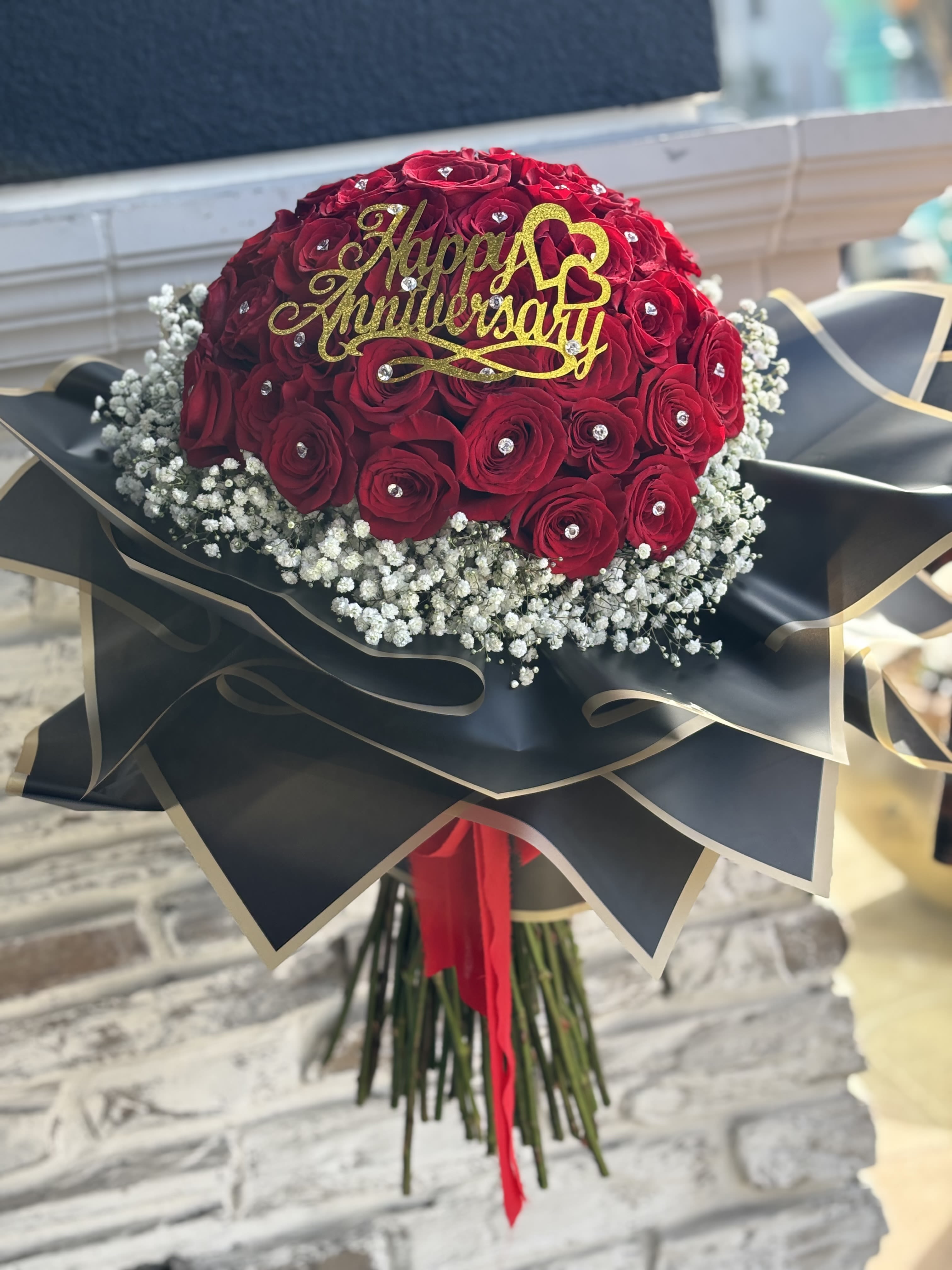 Ramo Buchon -50 Roses - 50 Long stem red roses surrounded with baby's breath wrapped in black and gold trim flower paper.  Rhinestones and Happy Anniversary/ Happy Birthday topper optional. ( please specify in special instructions).