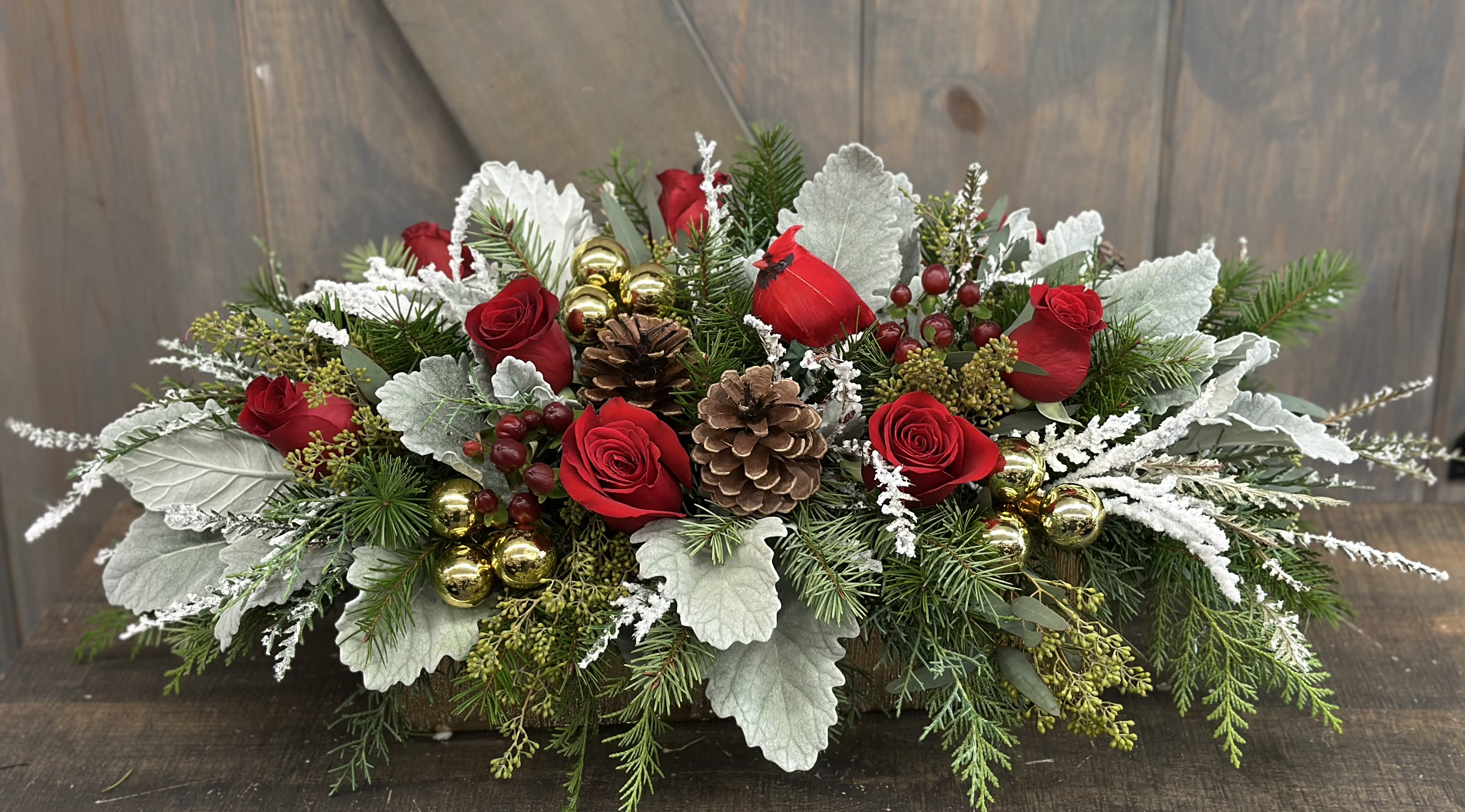 Cardinal Christmas - This elegant Christmas centerpiece has all the beautiful elements for a warm and inviting Holiday Display. Included in our design are Rose, Coffee Berry, Dusty Miller, and Mixed Winter greenery, Snowy pinecones, red glass ornaments, and an adorable miniature Cardinal faux bird