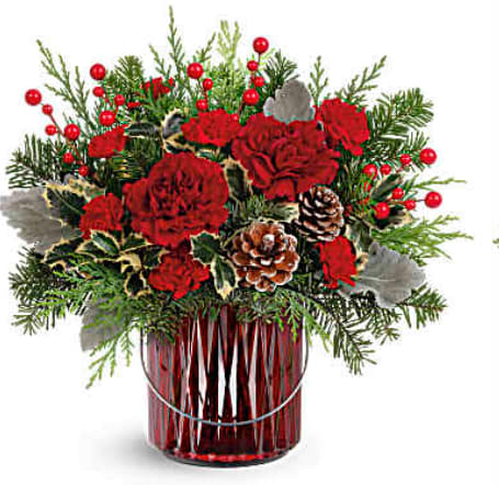 Merry Glow by Teleflora - Illuminate your holiday festivities with this enchanting Christmas bouquet, elegantly arranged in a red glass lantern. Later, it doubles as a beautiful candleholder, bringing a warm and festive glow to your home décor. (Roses in Deluxe and Premium only)