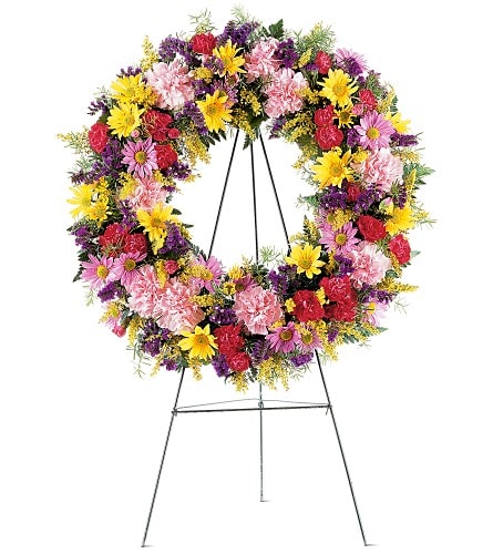 Eternity Wreath - TF189-8 - Show your love and support with this beautiful wreath of colorful mixed flowers. Its bright hues will lovingly grace the service. Each wreath is decorated with pink carnations lavender and yellow daisy chrysanthemums plus colorful fillers and soft foliages. The wreath is delivered on an easel.Approximately 24&quot; D As Shown : TF189-8