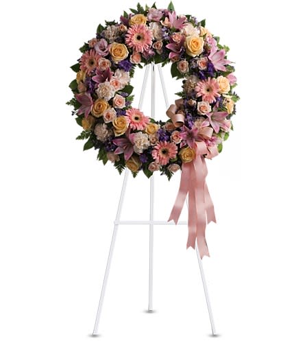 Graceful Wreath - T239-1A - Family and friends will recollect how special their loved one was with this gentle and timeless circle of fragrant blooms to celebrate sweet memories. A mix of flowers such as peach roses gerberas and carnations pink asiatic lilies and lisianthus purple limonium and lavender larkspur nest in greens on an easel-mounted wreath.Approximately 22 1/2&quot; W x 22 1/2&quot; H Orientation: One-Sided As Shown : T239-1A