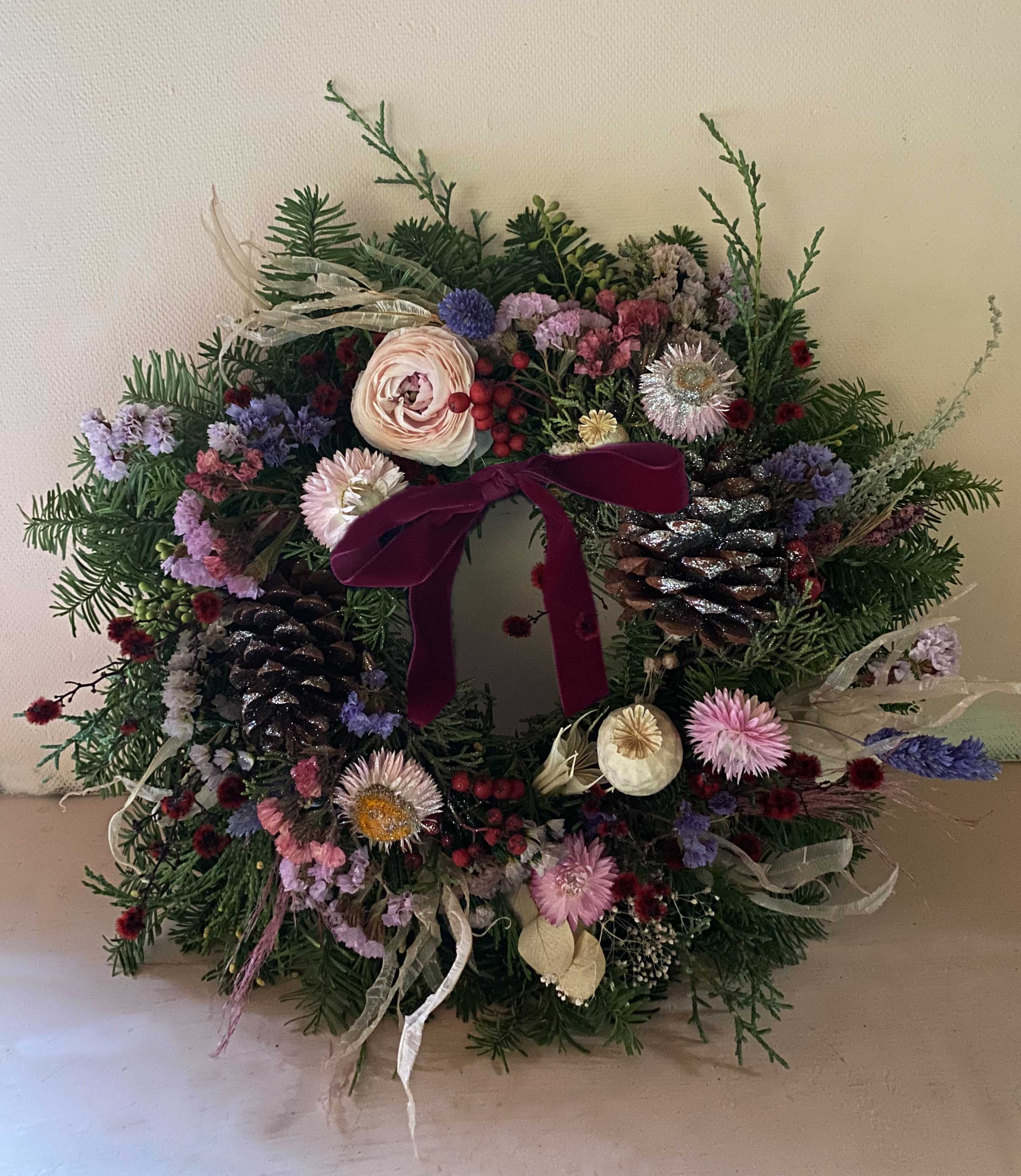 Blomst Holiday wreath - The most lovely wreath for the Holiday season of pine cones, dried and fresh flowers in a pretty colorful mix. Made on a base of different pines. Comes with beautiful red velvet ribbon and a hook to hang it in. Measures  appx 12&quot;