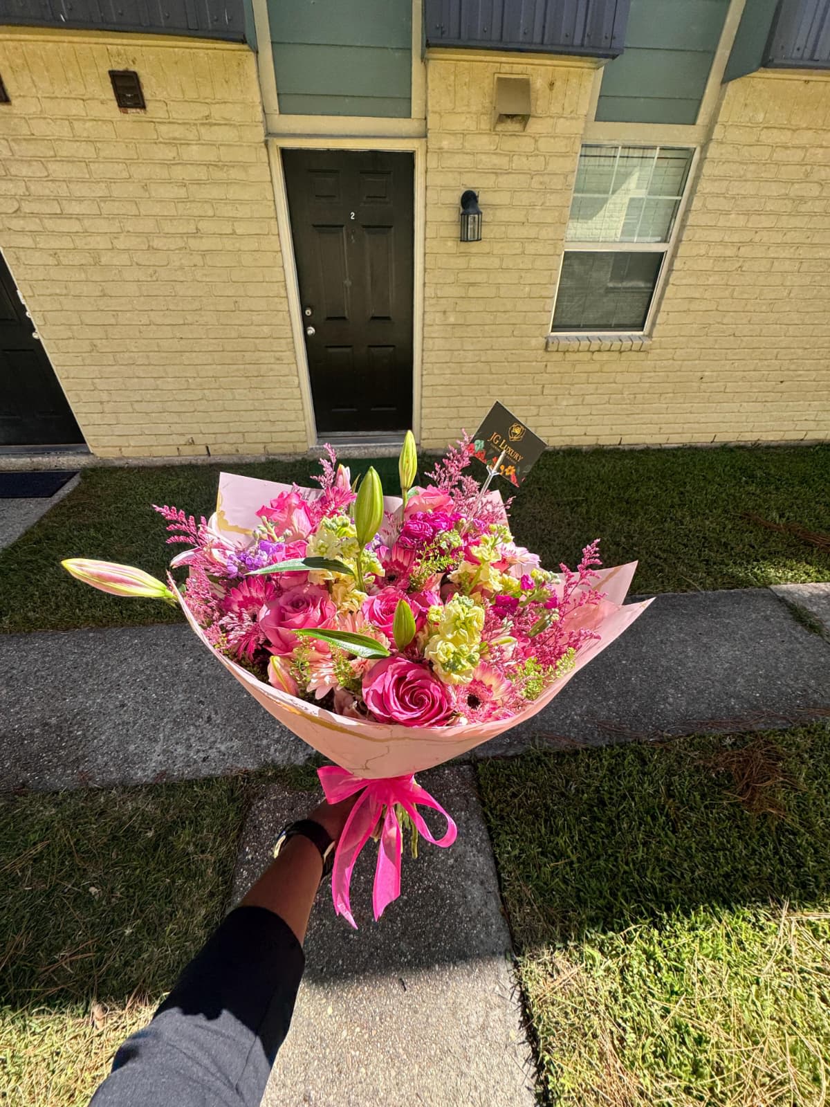Serenade - Charming bouquet bursting with shades of pink, featuring delicate roses, lilies, and seasonal blooms wrapped in soft blush paper and tied with a satin ribbon; the perfect gift to brighten someone’s day.