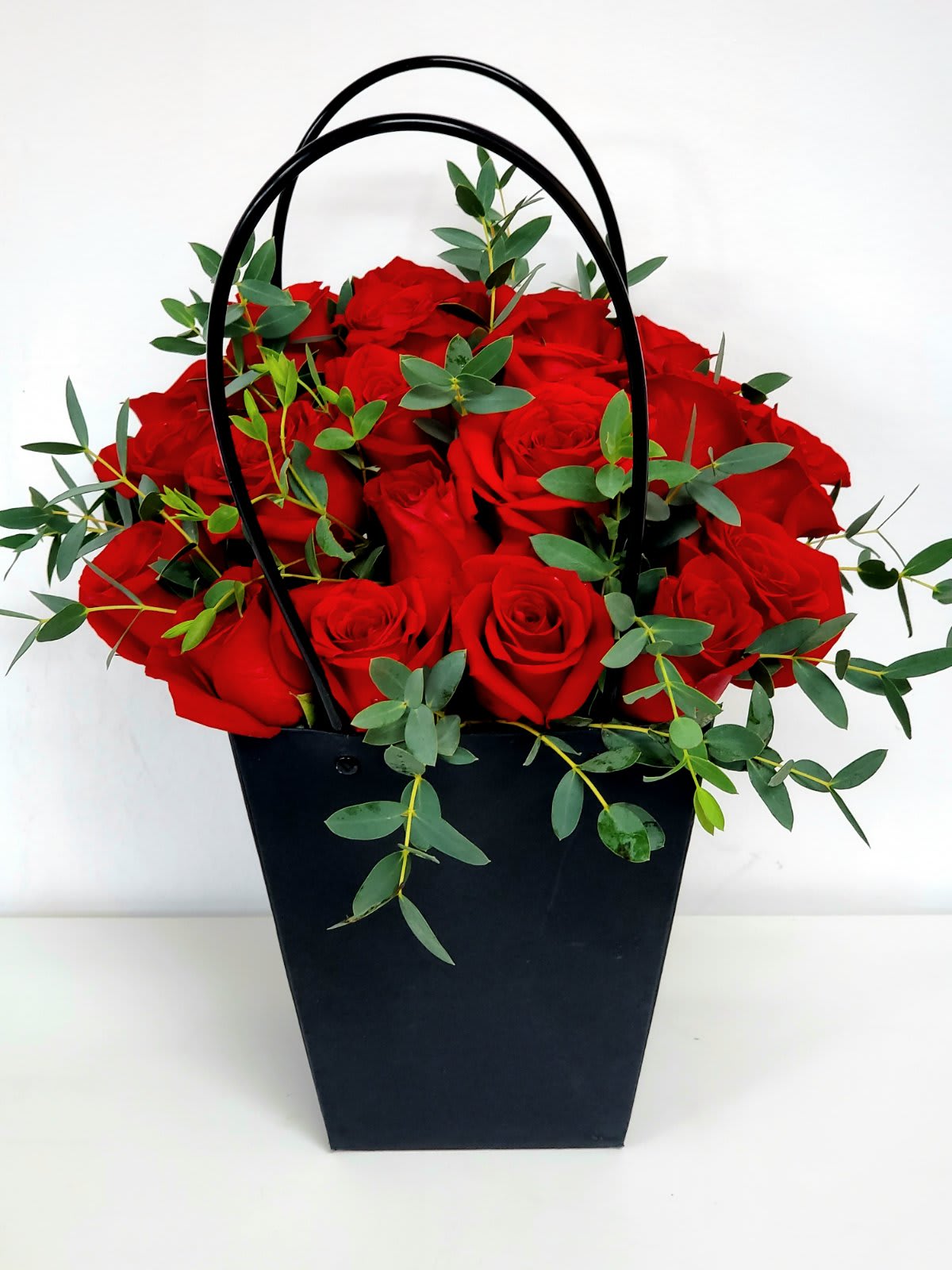 Red Roses in a Bag - Looking for eco-friendly arrangement?  Look no further.  The Red Roses in a Bag is perfect.  Simple yet Elegant and Luxurious made even more enchanting by the  dainty touches of parvifolia eucalyptus leaves. Want to make her proud? Send this unique bouquet any day... AS PICTURED: 2 DOZENS  20&quot;H by 15&quot;W  