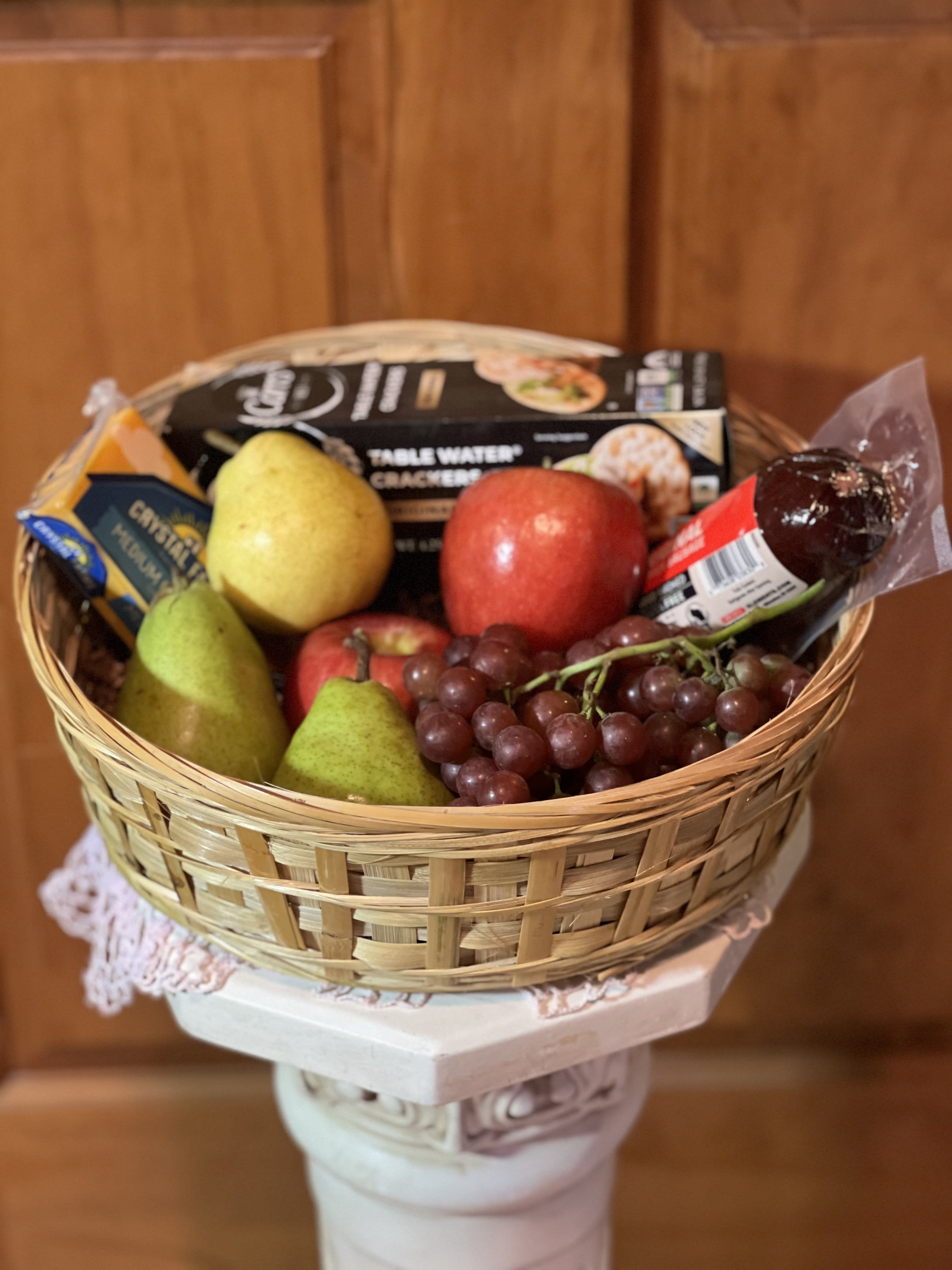 Fruit, crackers, cheese &amp; sausage gift basket. - Choice seasonal fruit, cheese, crackers &amp; sausage nestled in a reusable basket.  (Please specify type of cheese:  pick 1 choice-cheddar, brie, laughing cow wedges, string cheese) Sausage choice: pick 1- with garlic or without. Basket will differ from one shown. Basket will be round. Deluxe with come with a chocolate bar and fruit leather. (our choice)