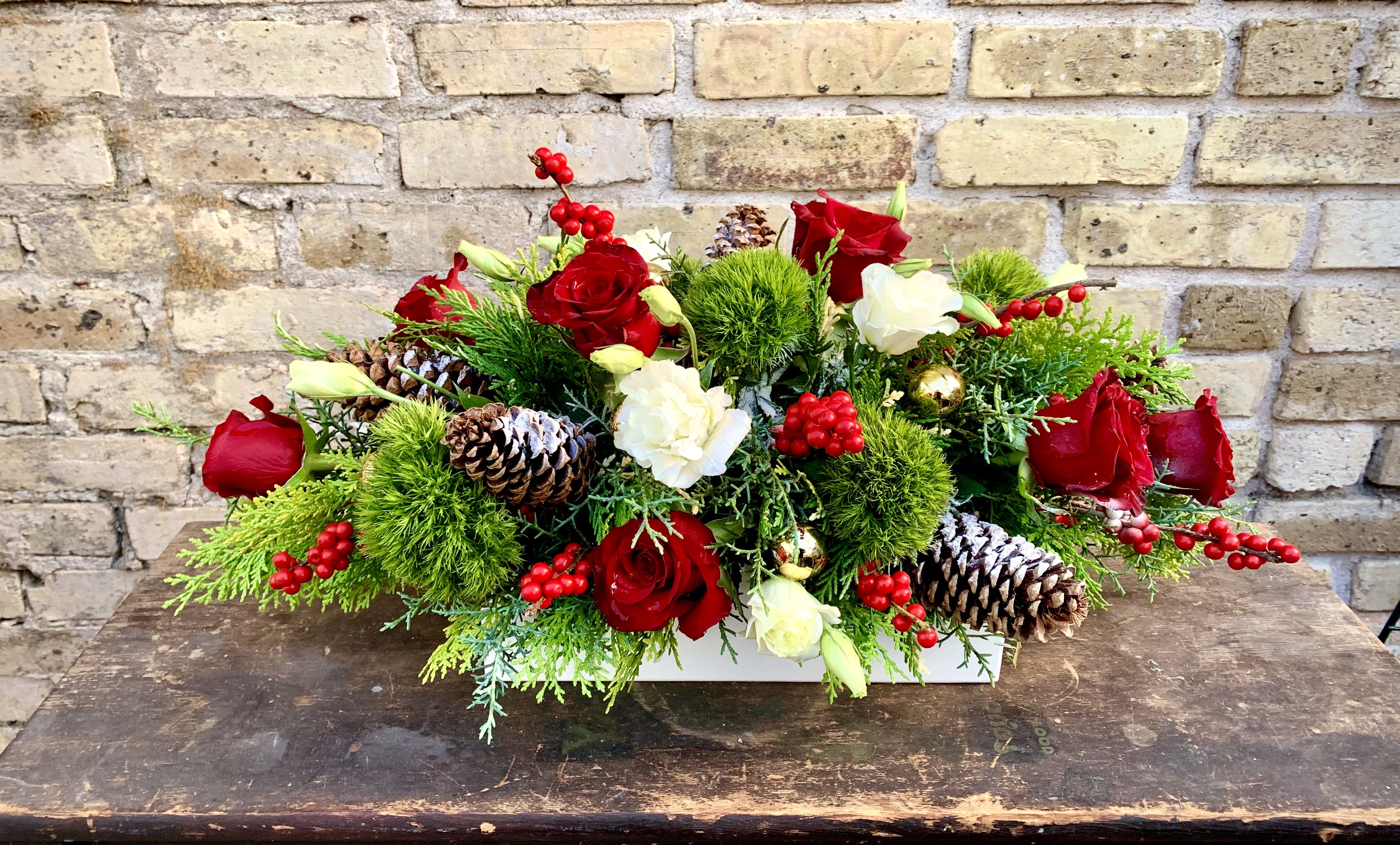 Holiday Glow - Elongated Fresh Arrangement Designed in a Rectangle Ceramic container. Red Roses, White Lisianthus and Green trick Make This a Beautiful Holiday arrangement with Holiday Accents. (flowers may vary depending on availability)