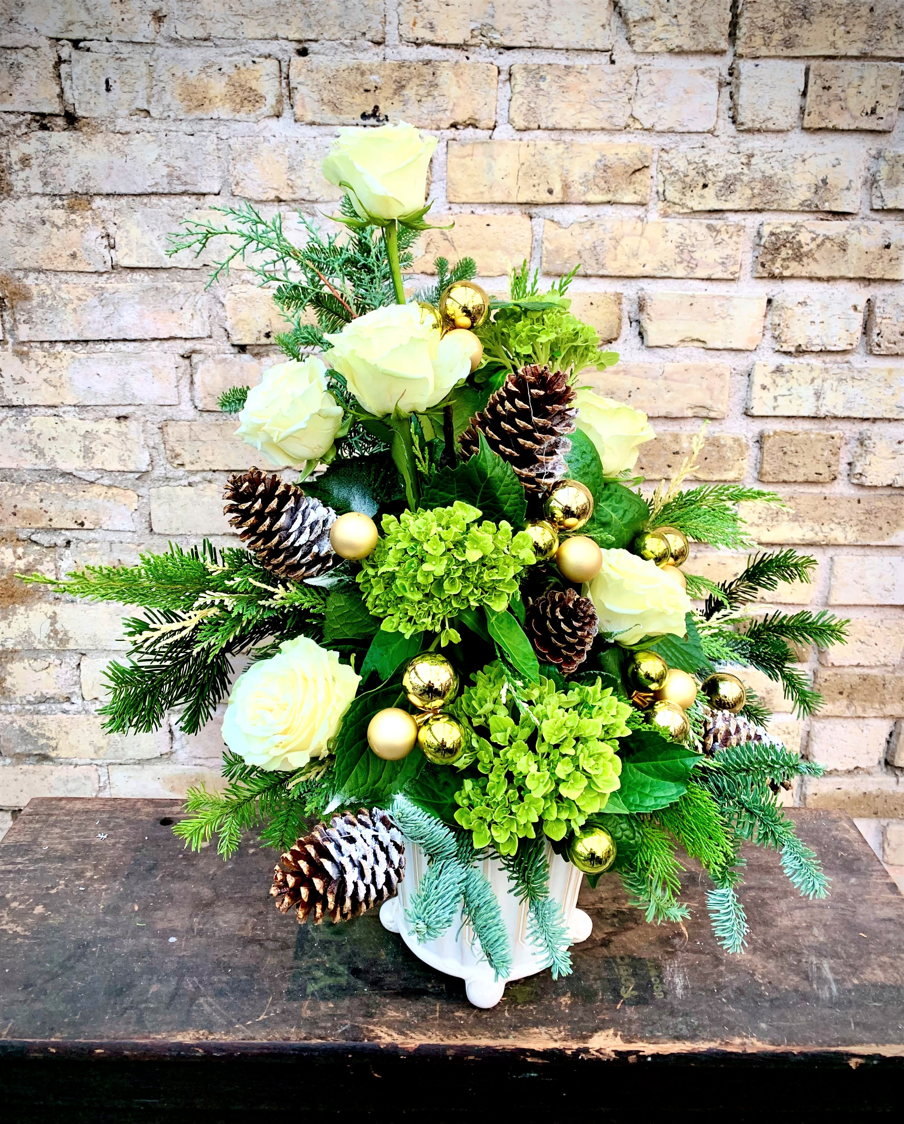 Winter Wonderland - Festive Arrangement Using Roses, Hydrangea, Pine Cones, Fresh Evergreens and Selection of Ornaments Will Make Any Gathering Memorable. Container May Vary.