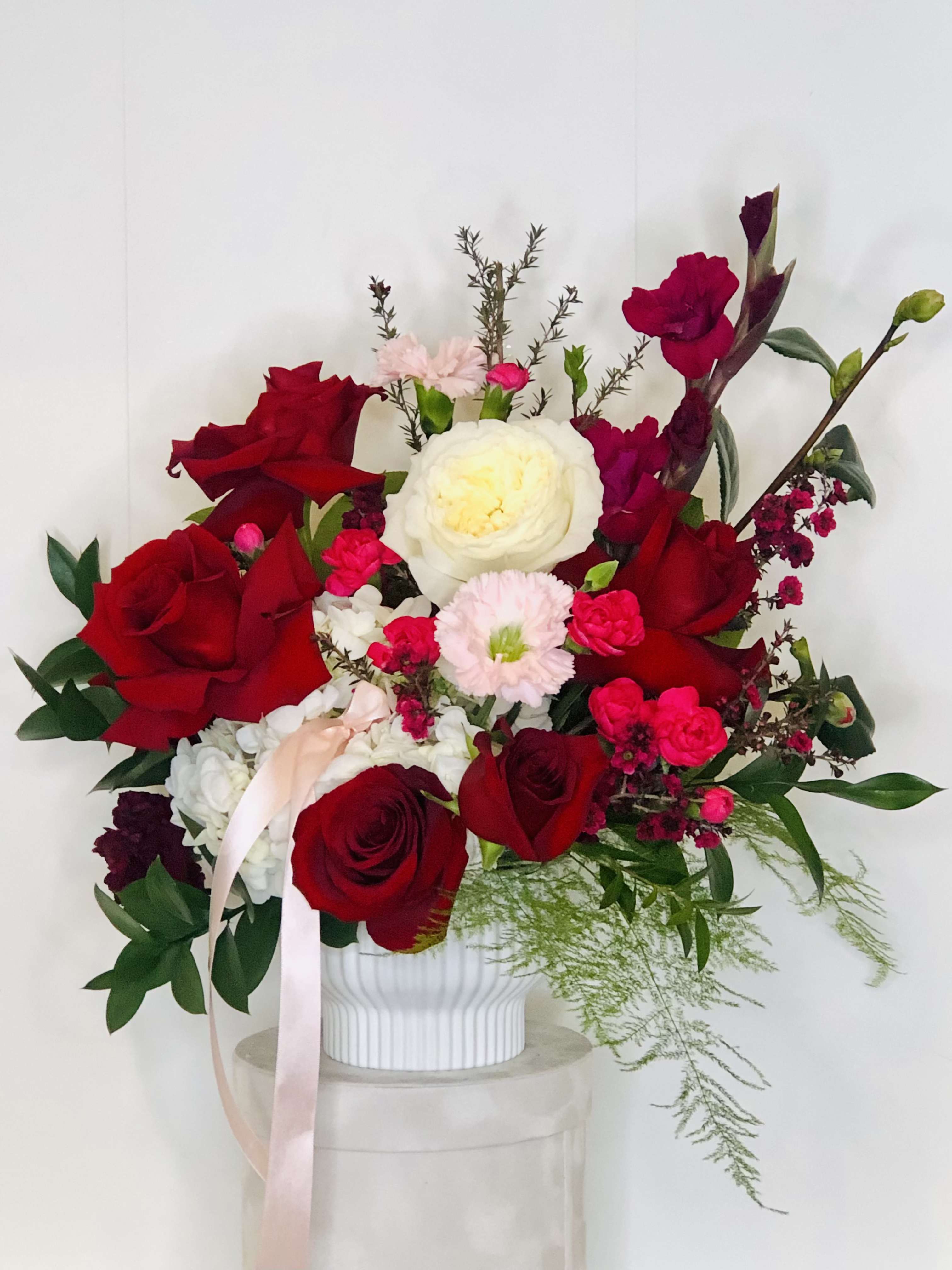 My Devotion - My Devotion is a breathtaking floral arrangement that embodies passion, elegance, and timeless romance. Featuring velvety deep red roses, each bloom symbolizes love and devotion, while lush garden roses add an extra layer of softness and charm. Delicate wax flowers weave through the arrangement, offering a subtle, sweet fragrance that enhances the romantic ambiance. Voluminous hydrangeas bring a sense of luxury and depth, their billowy petals complementing the rich textures of the roses. Luxurious greenery cascades throughout, adding balance, movement, and a touch of sophistication. Perfect for grand romantic gestures, My Devotion is a stunning expression of love and admiration, crafted to leave a lasting impression.