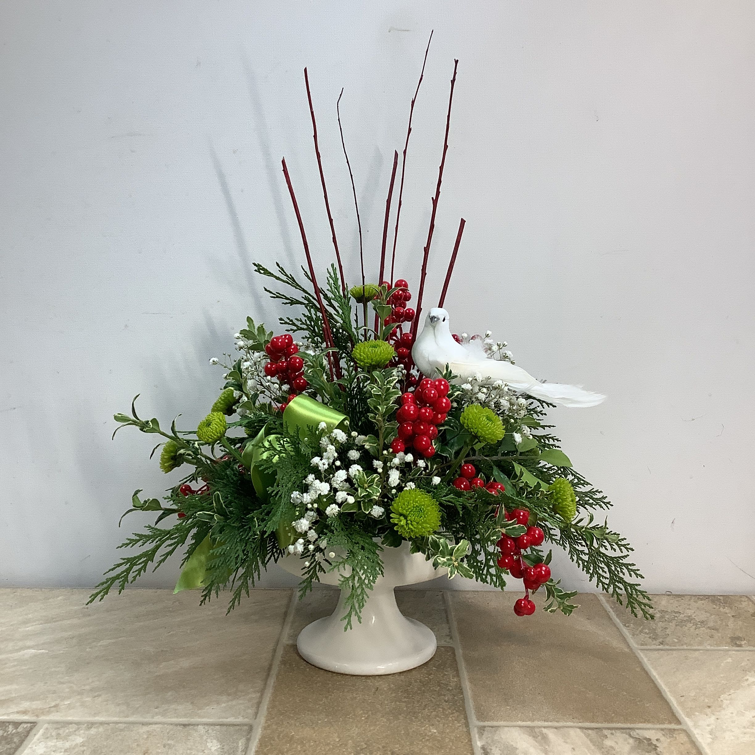Thoughtful - A thoughtful gift of fresh evergreens, baby’s breath and bright green Kermit poms expertly arranged in a ceramic pedestal vase. The lovely feathered dove nestled within makes this bouquet especially memorable. It measures 14” wide x 19” tall.  Primary flowers: mum, baby's breath