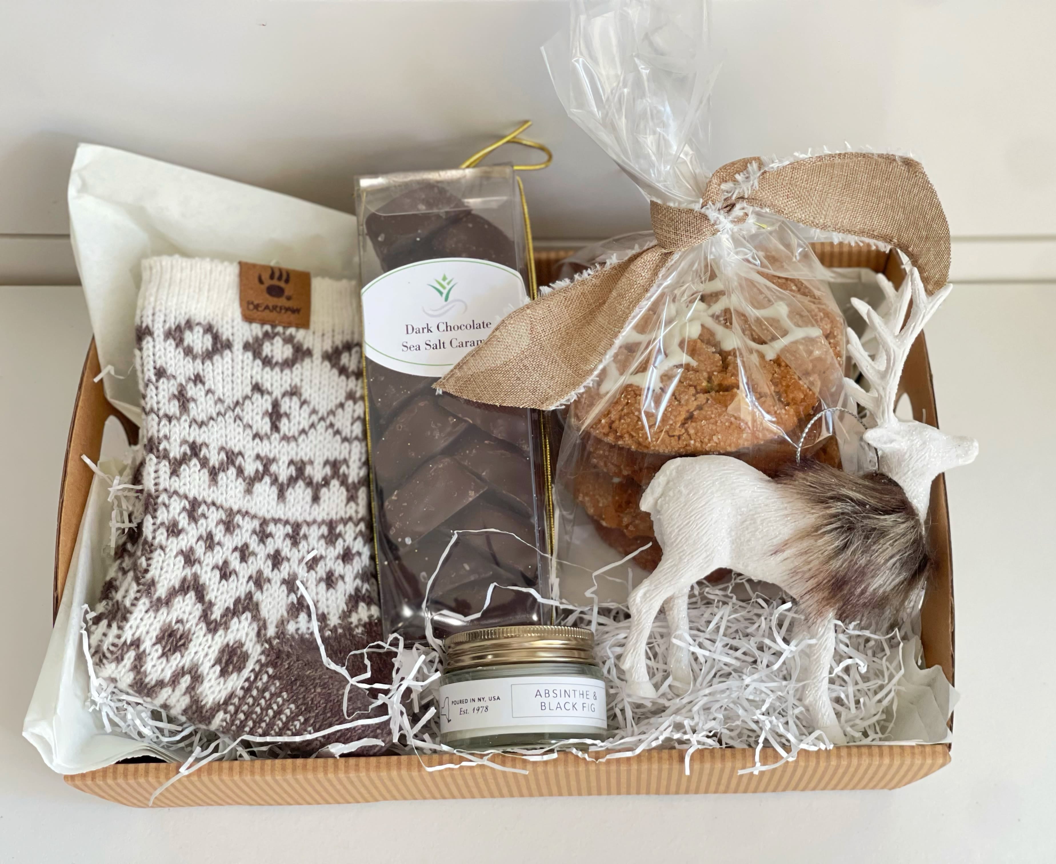 Christmas Mini with Candle - -cozy Bearpaw socks  -Dark chocolate sea salt, caramels  -fresh molasses ginger Christmas cookies  -mini black fig candle by Northern lights  -reindeer decoration  Wrapped in cellophane and tied with a Christmas ribbon
