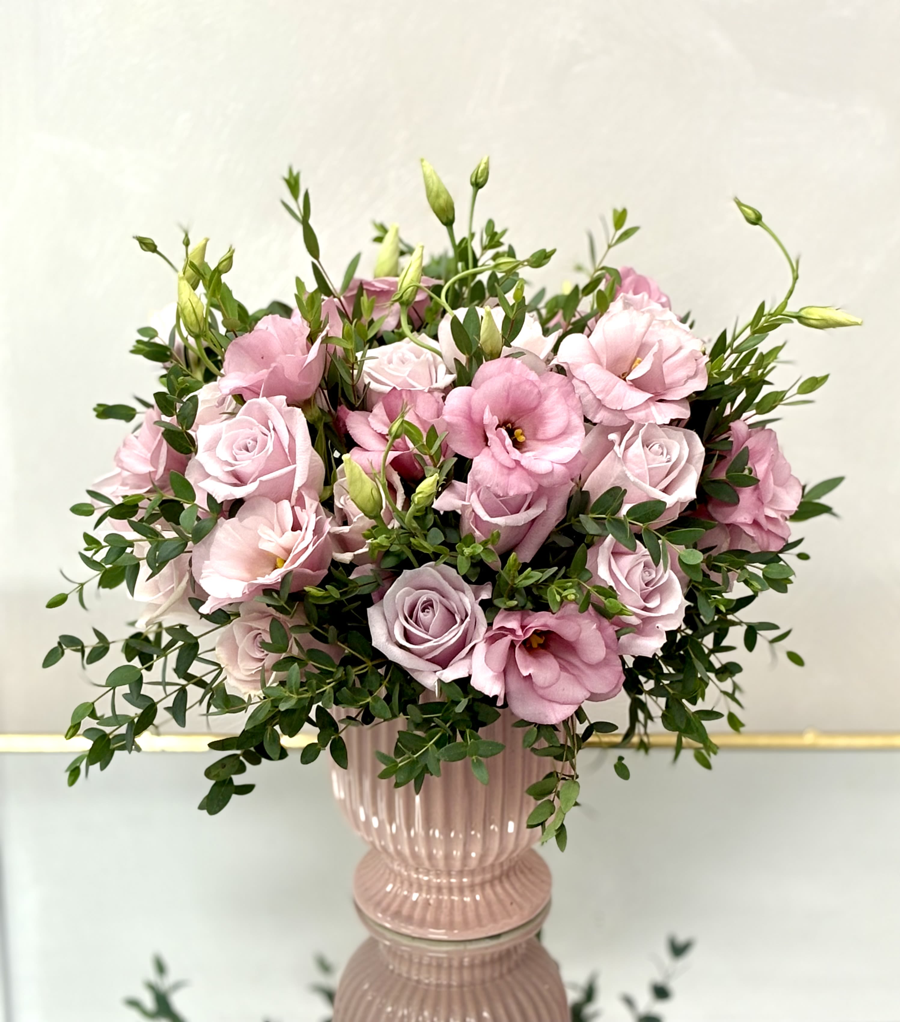 Pastel Charm By VLM Flowers - A graceful blend of soft pink roses and lisianthus with lush greenery, creating a delicate and romantic display that brightens any setting.