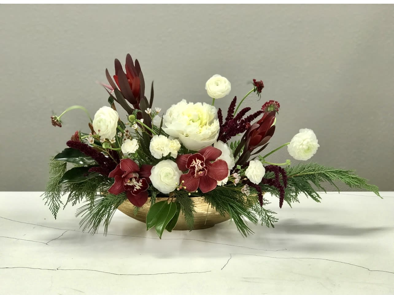 Popcorn Strand - Ring in the Holiday Season with our Scandinavian-Inspired Floral Arrangement! Featuring rich burgundy cymbidium orchids, elegant white peonies, textured safari sunset, burgundy amaranthus, and seasonal greens, this design captures the perfect balance of minimalistic beauty and wild winter charm.  A stunning centerpiece for any December celebration — warm, modern, and effortlessly festive.