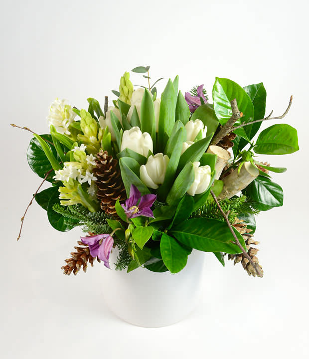Forest Nights - White tulips, hyacinth, hydrangea and winter pine accented with pine cones and birch and gardenia foliage in our white ceramic vase.