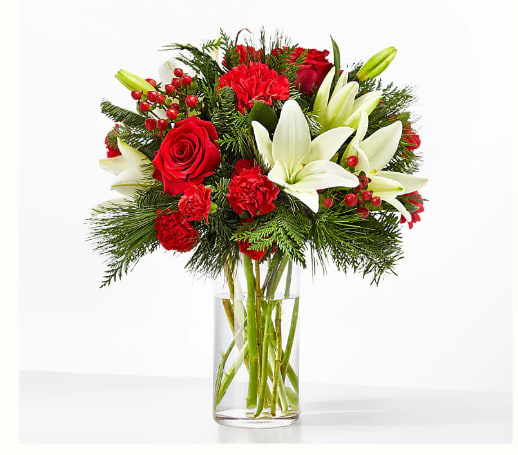 Joyful Greetings Bouquet - Spread cheer to your loved ones near or far with the Joyful Greetings Bouquet, full of cozy red and white blooms perfectly capturing the holiday spirit. Details Designed by florists, ready to display. For long–lasting blooms, replace the water daily. We suggest trimming the stems every couple days. Bloom Details: Roses, Lily, Carnations