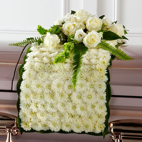 The Blanket of Flowers - The Blanket of Flowers is a beautiful adornment for the top of their casket at the final farewell service. White chrysanthemums form a blanket of blooms that drape across the casket accented with an arrangement of white roses, white double lisianthus, Bells of Ireland, ivy sword fern and a variety of lush greens to create an exquisite look of sweet serenity to honor the life of the deceased.