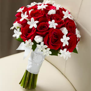 The Poetry Bouquet - Our Poetry Bouquet has a look of pure elegance and charm that will make you look your bridal best. Red roses are accented with white tulips and white stephanotis blooms beautifully tied together with a white French taffeta ribbon to give you an appearance that only poetry could describe. NOTE: 2 WEEK PRE-ORDER REQUIRED. White stephanotis is a special order flower each one of those tiny white blooms is 8.00 each bud. We can lower the price of this bridal bouquet just give us a call and we can create one that is just right for you.