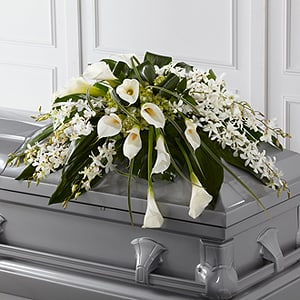 The Angel Wings Casket Spray - The Angel Wings Casket Spray is an exceptionally gorgeous way to bring peace and beauty to their final farewell service. White Dendrobium orchids, white calla lilies, green hydrangea and a variety of lush greens are artfully arranged to perfectly adorn the top of their casket offering the colors and ambiance of grace and serenity. Up to 2 weeks notice for this one. Orchids are flown in. 