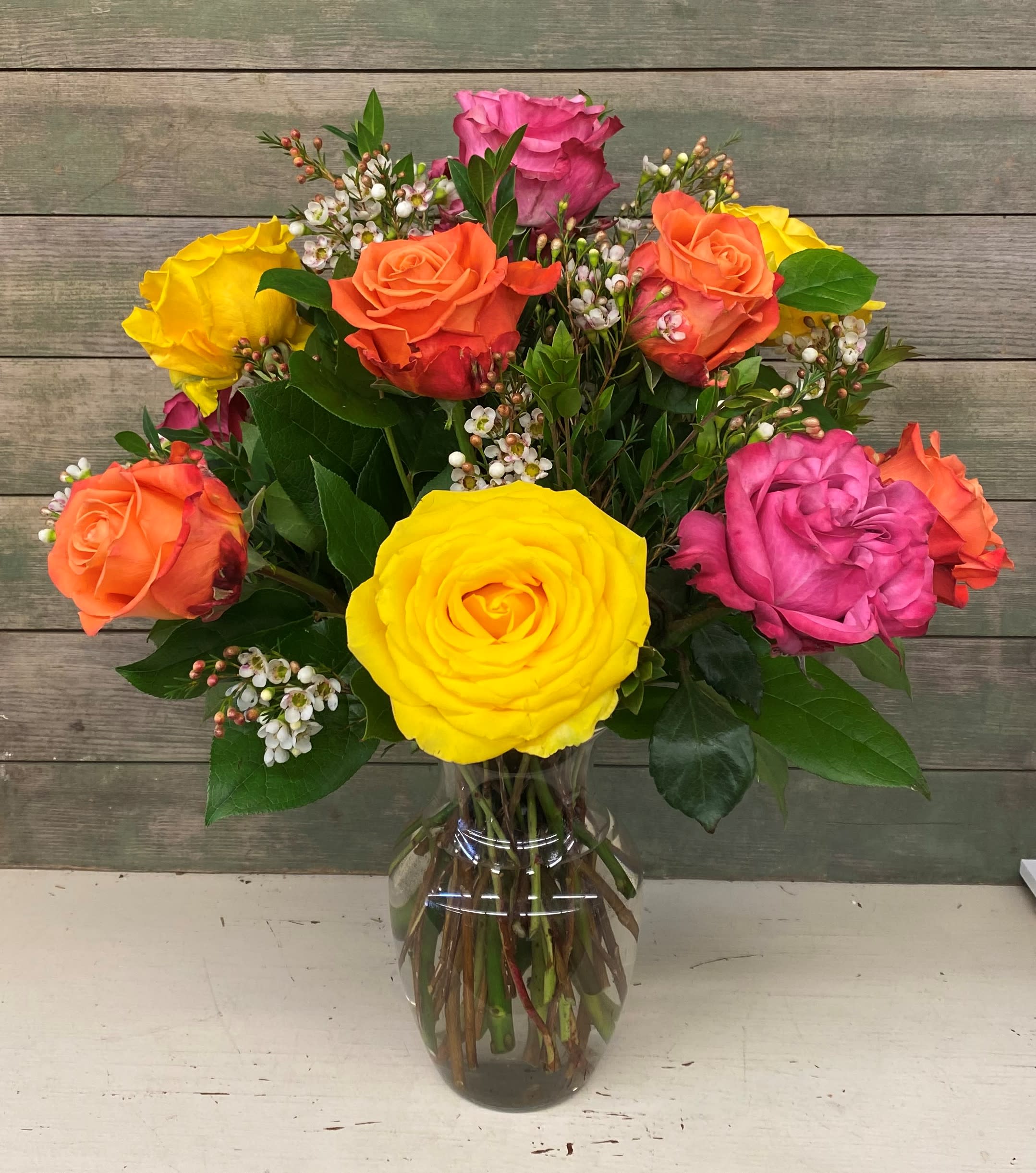 Dozen Roses - Mixed Colors - This classic arrangement features 12 mixed colored roses with premium greens and filler. Note: rose colors, greenery, and filler flowers may vary from photo.