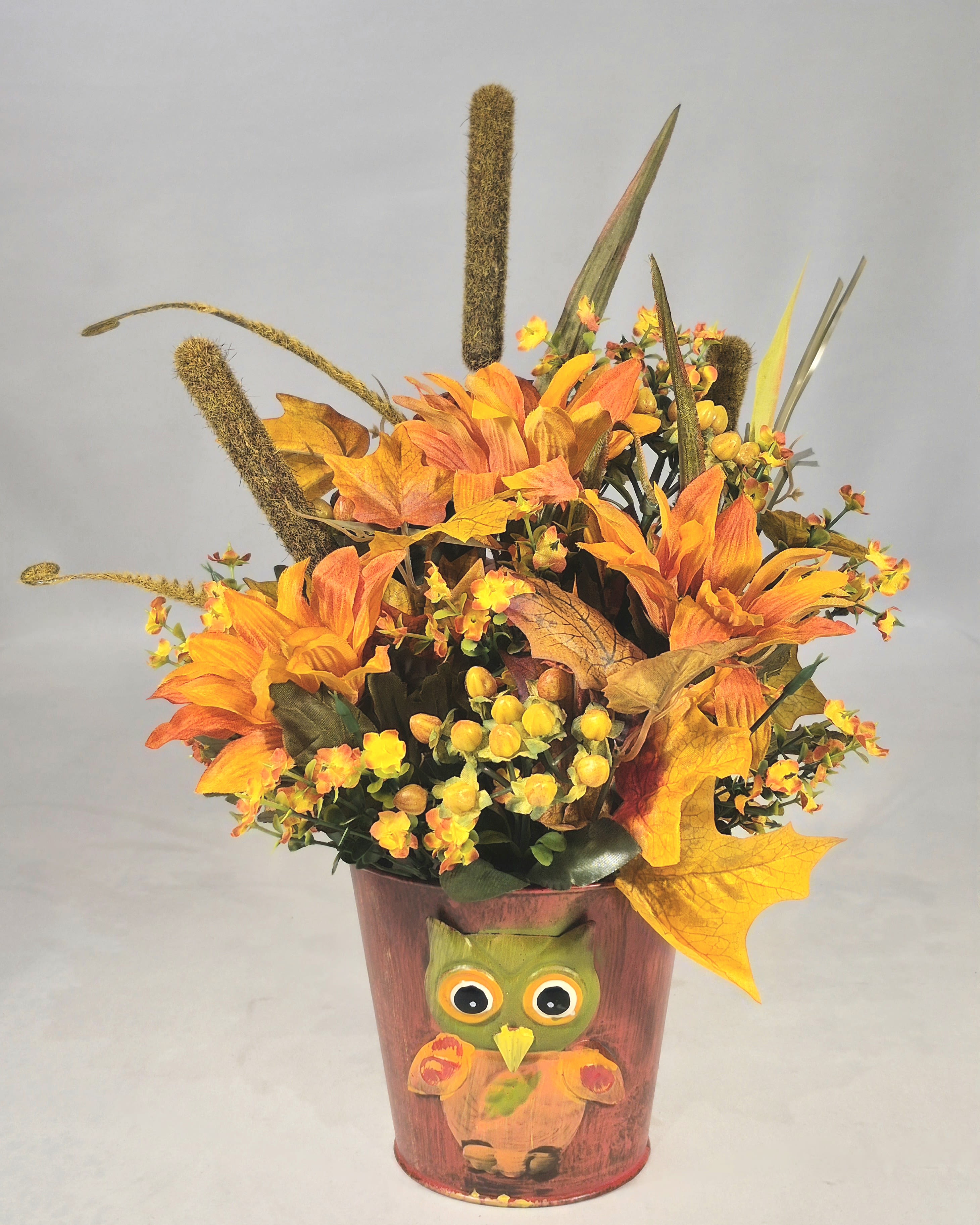 Autumn Owl Silk Arrangement - This fall silk floral centerpiece with orange sunflower's, leaves and more will add to your fall decorations or send to brighten someone's day. This cute arrangement will add a cozy feel to any room for the fall season.  14&quot; T 10&quot; W