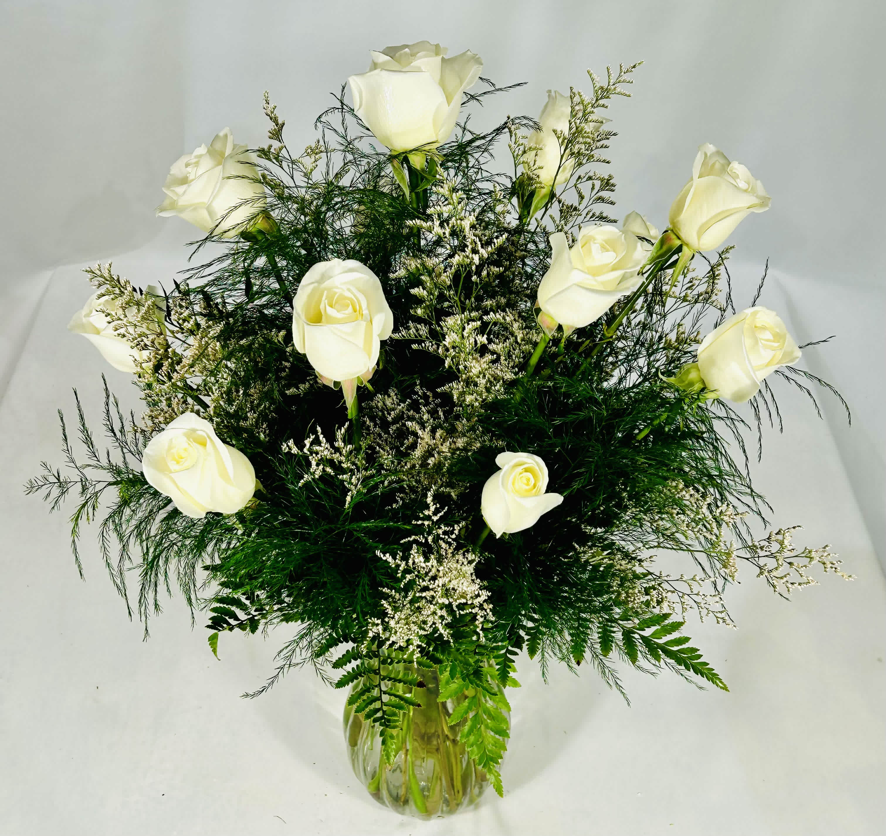 Dozen White Roses - A dozen white roses are a classic gift! Perfect for Valentine's Day, an Anniversary, or any type of celebration. Surprise your special one with this gorgeous arrangement. A dozen beautiful, fresh-cut, White Roses, designed with white fillers and greens in a rose vase.  25&quot; H X 18&quot; W Standard - Dozen White Roses as pictured. Deluxe - 18 White Roses Premium - 2 Dozen White Roses  
