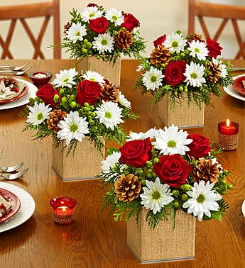 Colors of Christmas Centerpieces - Spread a whole lot of holiday cheer across the table or throughout the house! Our compact wooden box (white) centerpiece is filled with vibrant roses, joyful daisy poms and assorted Christmas greens, then topped off with pinecones all hand-arranged inside a wooden box (white) for a modern touch. Available as a set of two (regular), three (deluxe) or four (premium), it makes a fun parting gift for your party guests, too!  Each arrangement arrives fresh and blooming. We select the freshest flowers available, so colors and varieties may vary due to local availability