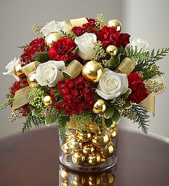 Glorious Christmas - Product ID: 99076  Here's one Christmas bouquet that will leave everyone ooh-ing and ahh-ing! Artfully crafted from  roses, rich burgundy dianthus and carnations and assorted evergreens, it is gathered fresh in a classic glass vase filled with shimmering ornament balls. Finished off with gold ribbon, we think you will agree, this gift is equally as stunning as a centerpiece, thank you gift or winter birthday surprise.   