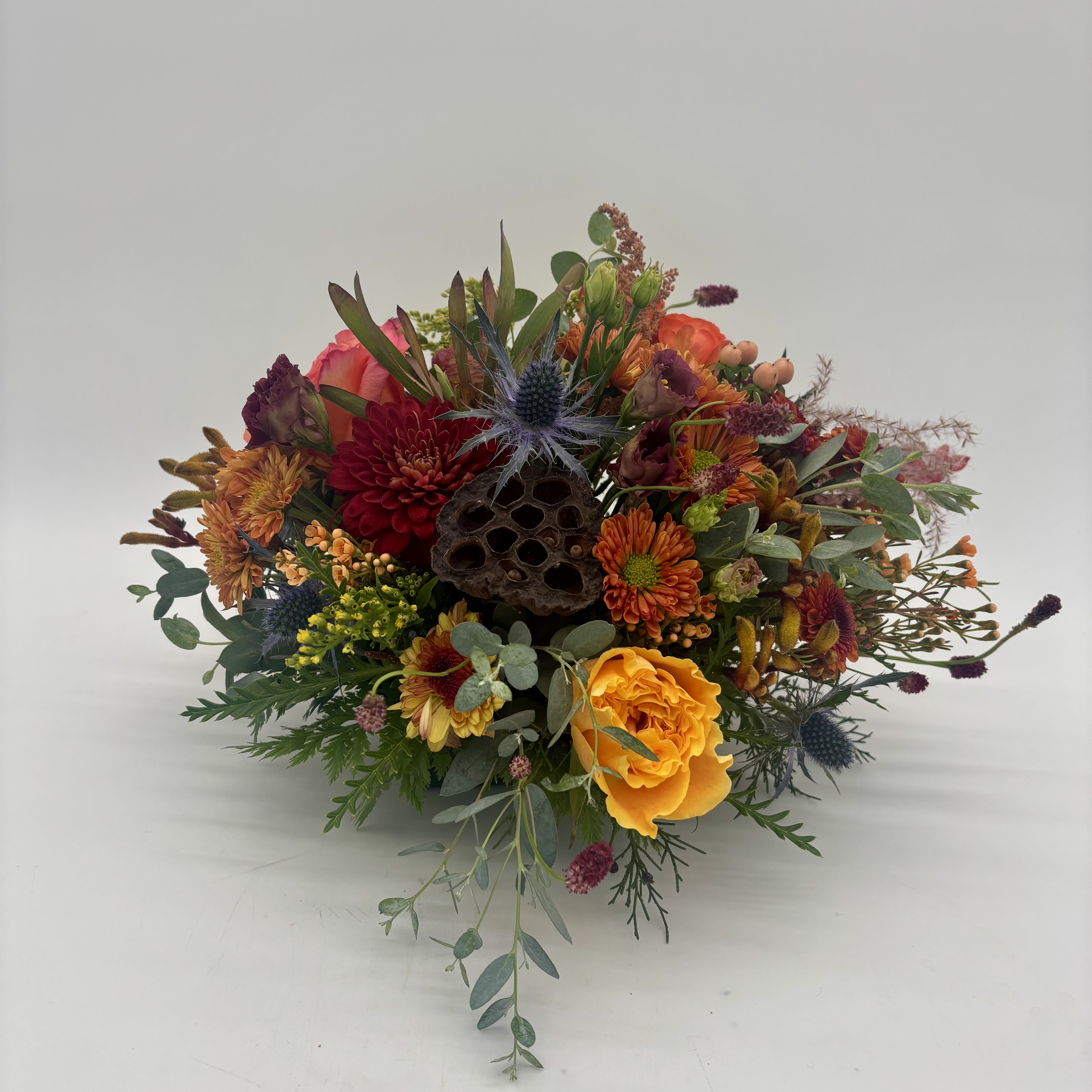 Round Centerpiece - Traditional centerpiece made in 6&quot; designer dish. Included but not limited seasonal fall tones - oranges, yellows, reds, burgundies and dried material. Upgrade with a candle. Call the studio with specific request. Will be made as similar as possible but designers reserve the right to substitute based on available inventory. 