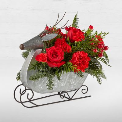 Prancer Bouquet - Fly into Christmas Eve with this dashing Prancer Bouquet designed in a festive reindeer sleigh. All your holiday favorites like red blooms, hypericum berries and evergreen accents will drape over the playful reindeer, bringing the Christmas spirit to any room.