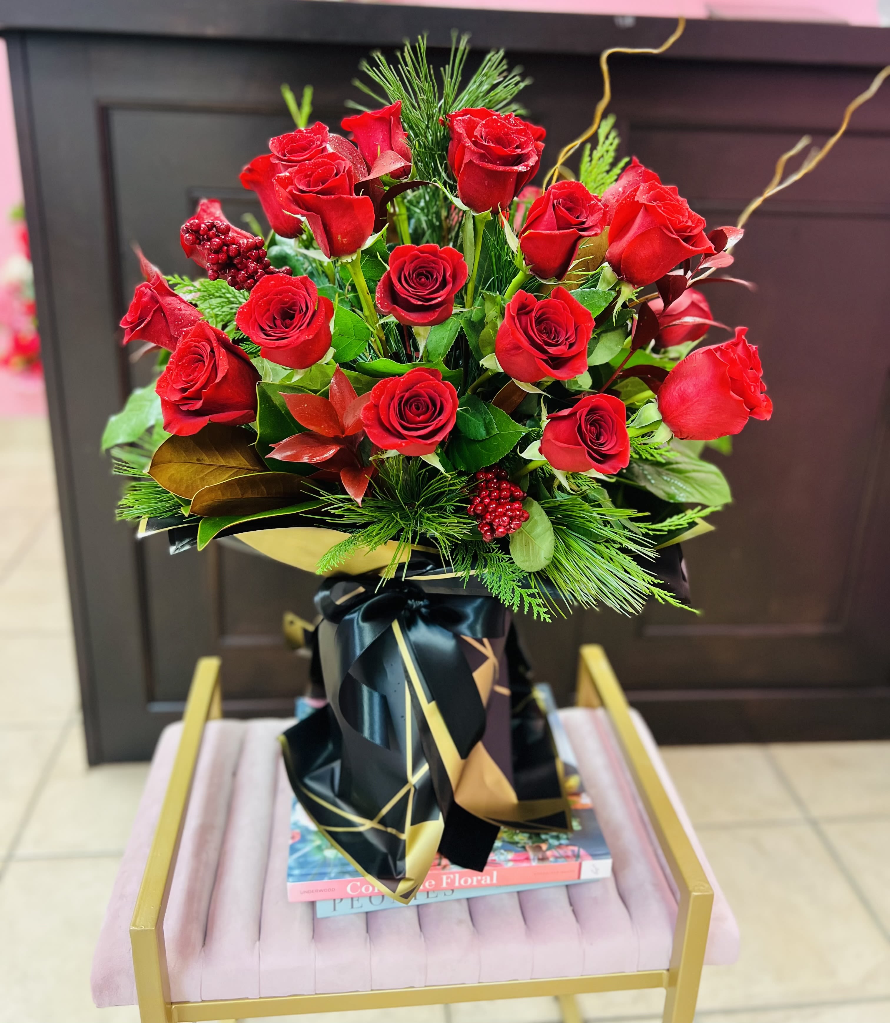 Holiday Crimson Luxe - Elevate the season with Holiday Crimson Luxe, a dazzling Christmas arrangement featuring lush premium red roses, festive winter greenery, and vibrant red berries. Designed in a clear glass vase wrapped in black-and-gold waterproof floral paper, this piece blends modern elegance with classic holiday charm. Perfect for gifting, celebrating, or bringing a luxurious seasonal glow to any home or event. 