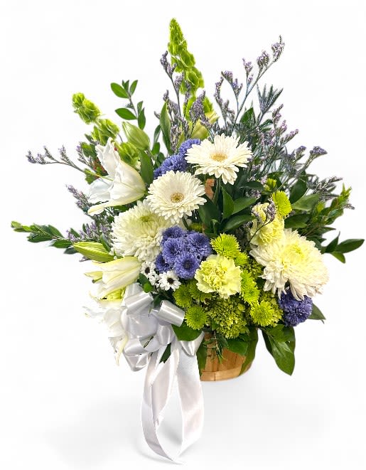 Lush Tranquility Basket - This flower basket features a lovely yet soft arrangement of flowers in shades of white, green, and blue.  The bouquet includes lilies, carnations, daisies, and various greenery, all presented in a light brown wicker basket. A white ribbon box is included and placed neatly to complement the basket, adding a touch of elegance to this beautiful basket arrangement.  