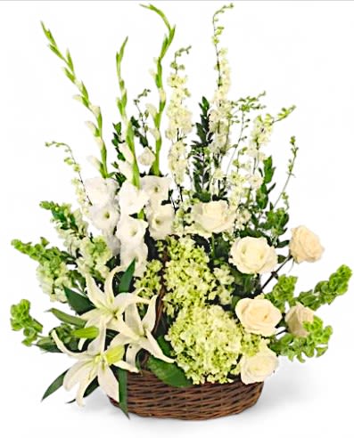 Peaceful Eternity Basket - This elegant sympathy arrangement is presented in a charming wicker basket adorned with a handle and liner, exuding warmth and comfort during difficult times. It features lush myrtle foliage, which adds a soothing, natural element. Five striking bells of Ireland stand tall, symbolizing good luck and new beginnings, while three pure white gladiolus and three graceful snapdragons enhance the arrangement with their elegant forms. Among them are three delicate stems of white larkspur and three pale green hydrangeas, adding layers of texture and tranquility. Completing this heartfelt tribute are seven pristine white roses and three stunning white lilies, representing purity and remembrance. Together, these blooms create a serene and uplifting tribute, offering solace and love to those grieving a loss.