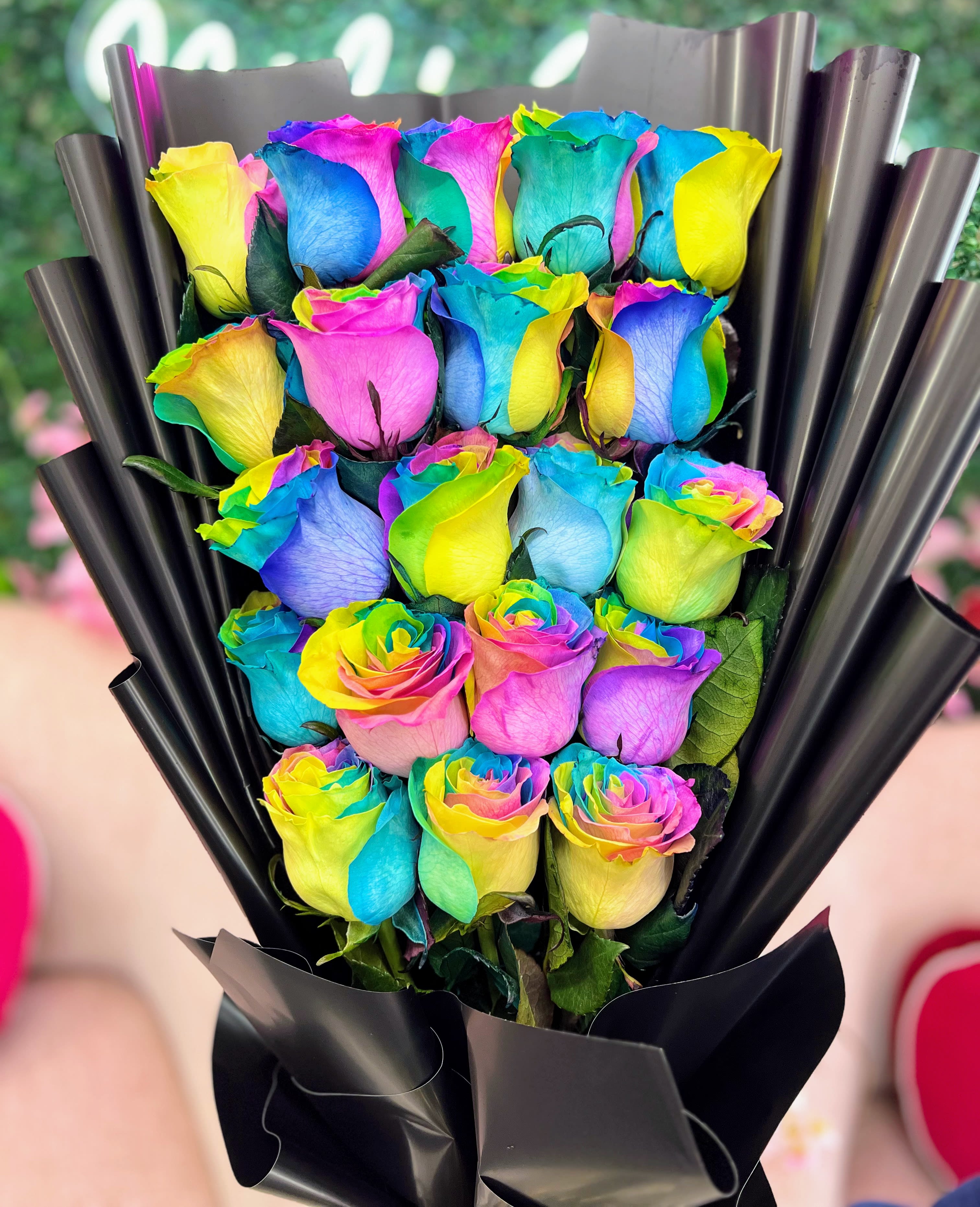 Wrapped Rainbow Rose Bouquet - Brighten any moment with this vibrant Wrapped Rainbow Rose Bouquet. Each rose is carefully tinted to display a full spectrum of color, symbolizing joy, diversity, and celebration. Wrapped in elegant paper and tied with a satin ribbon, this bouquet is both striking and meaningful — perfect for birthdays, anniversaries, pride events, or simply to add a pop of color to someone's day. STANDARD 12 ROSES DELUXE 18 ROSES PREMIUM 24 ROSES