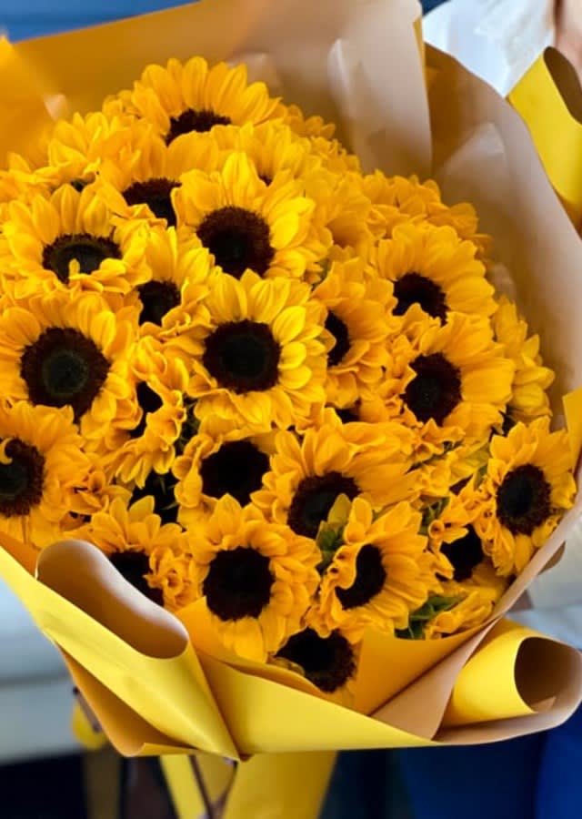 Amber Skies Wrapped Bouquet - Amber Skies Wrapped Bouquet include fresh sunflowers!  Our loose bunches are designed with fresh flowers, individually created by our designers, wrapped, and finished with a lovely bow. These bouquets will vary daily based off of the best seasonal selection.  Our loose bunches do NOT include vases. Paper and bow color will vary.