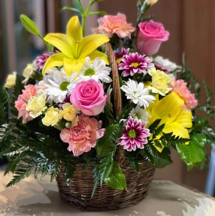 Full of Love - A wicker basket filled with lilies, roses, carnations and daisies. Sweet pinks, pops of yellow and white accents perfect for any occasion. The container may vary depending on availability. Bouquet may be sent in a basket, a metal or a plastic container.