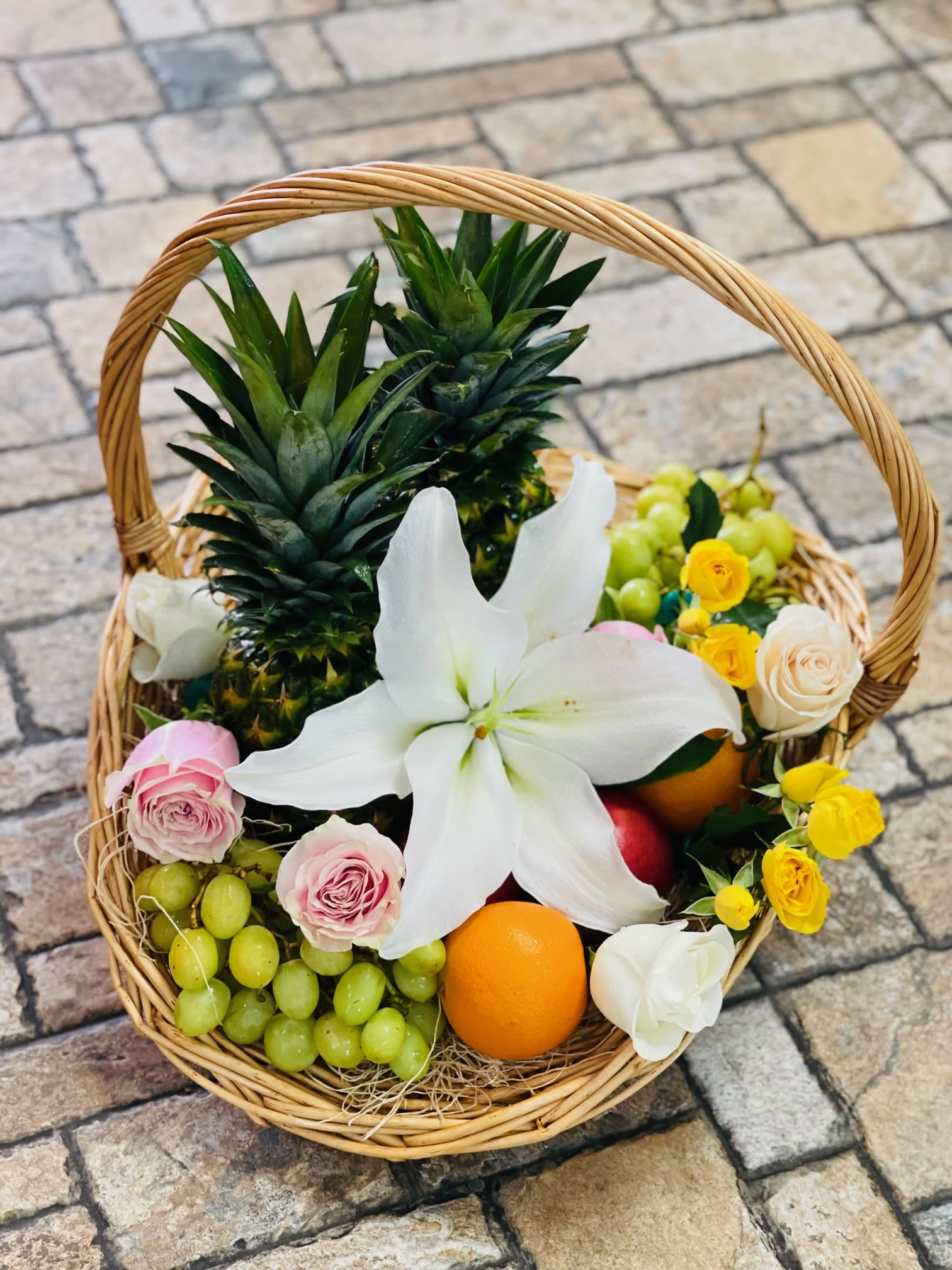 Tropical Fruit Basket - Fresh cut tropical flowers and assorted fresh fruits arranged in a rustic basket. With a mix of fresh flowers and fruits, this stunning basket is perfect for any occasion. *Fruits, flowers and basket may vary*