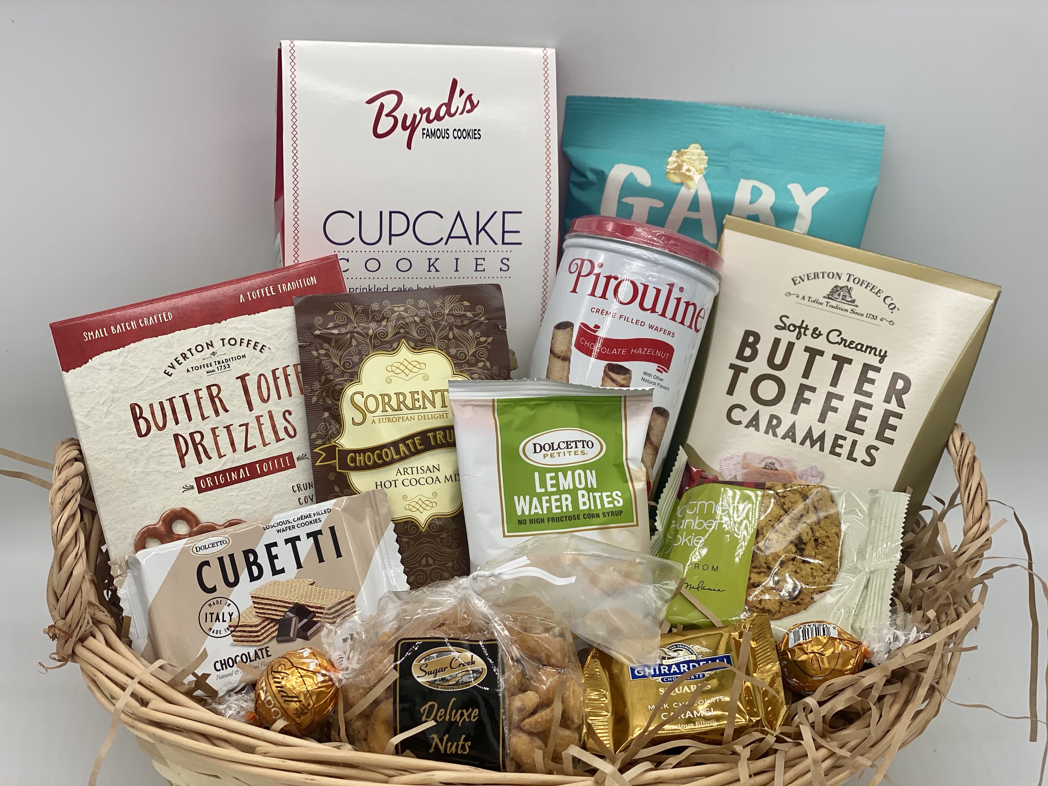 Small Gourmet Basket  - A basket full of gourmet goodies!  Designed in an oval wicker basket this basket includes cupcake batter cookies, pirouline wafer tin, butter toffee caramels,  sea salt popcorn, butter toffee pretzels, hot chocolate, wafers, nuts and chocolates! 