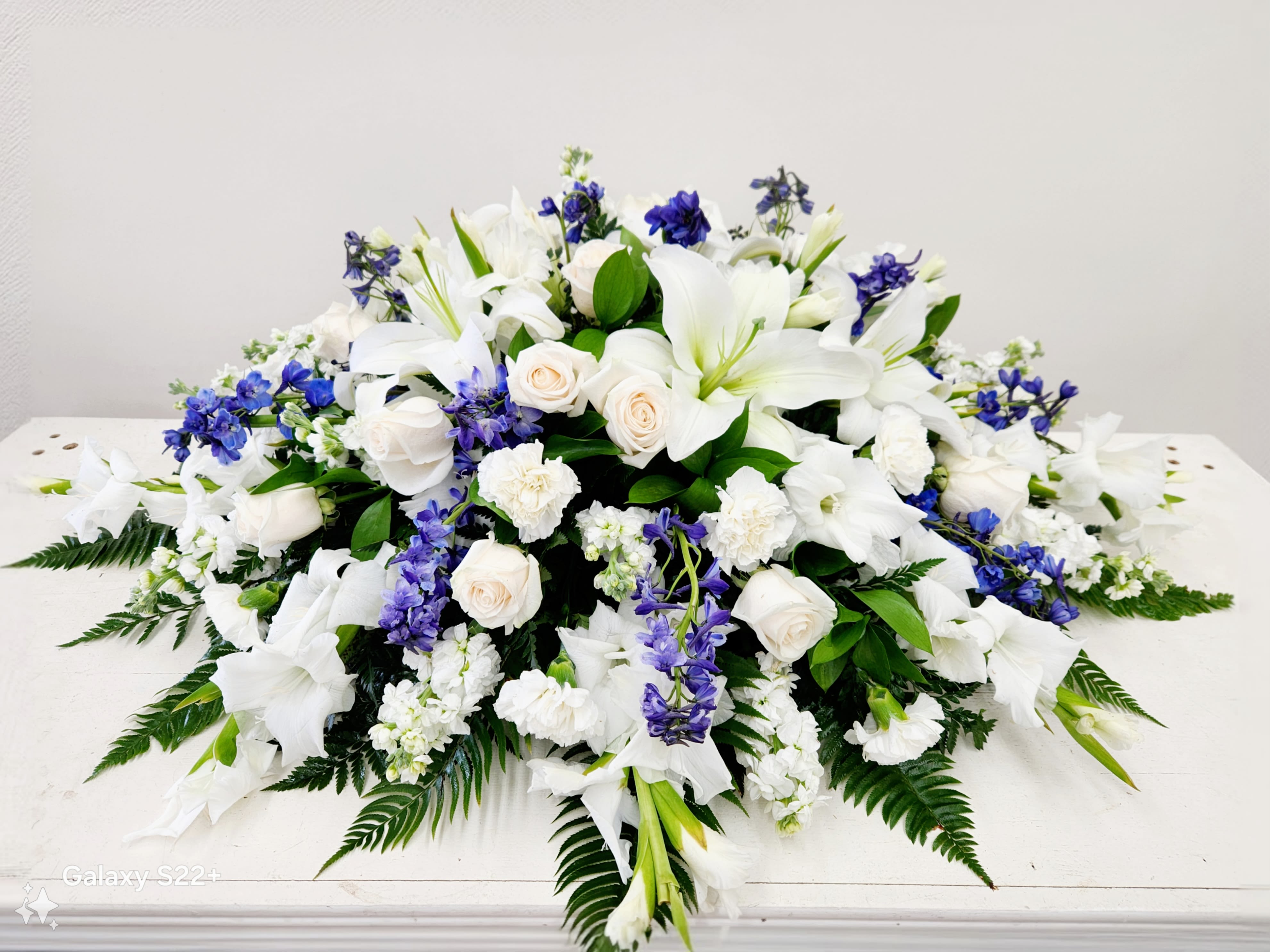 Blue and White Casket Spray - This Blue and White Casket Spray offers a timeless, elegant tribute crafted with care. Featuring a harmonious blend of soothing blue and pristine white flowers, it conveys heartfelt sympathy and respect. Perfectly arranged to provide a beautiful, classic expression of support during difficult times, this spray delivers a meaningful farewell with grace and dignity.  Premium - As Pictured: &quot;52&quot;L X 32&quot;D
