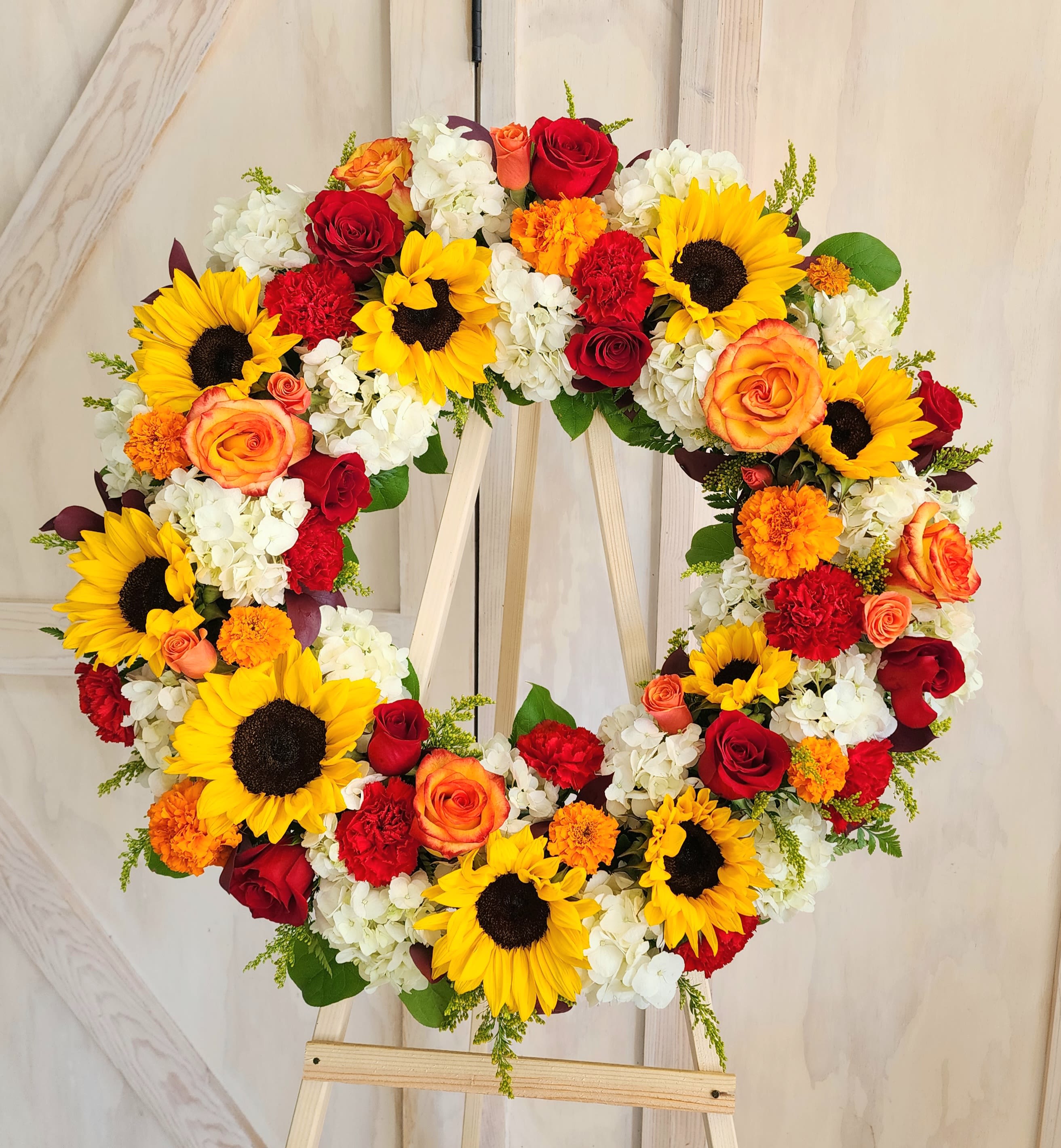 Sunflower Love Sympathy Wreath  - Red roses with beautiful  sunflowers and high magic roses designed around fluffy hydrangea, red carnations and yellow or red fillers. 