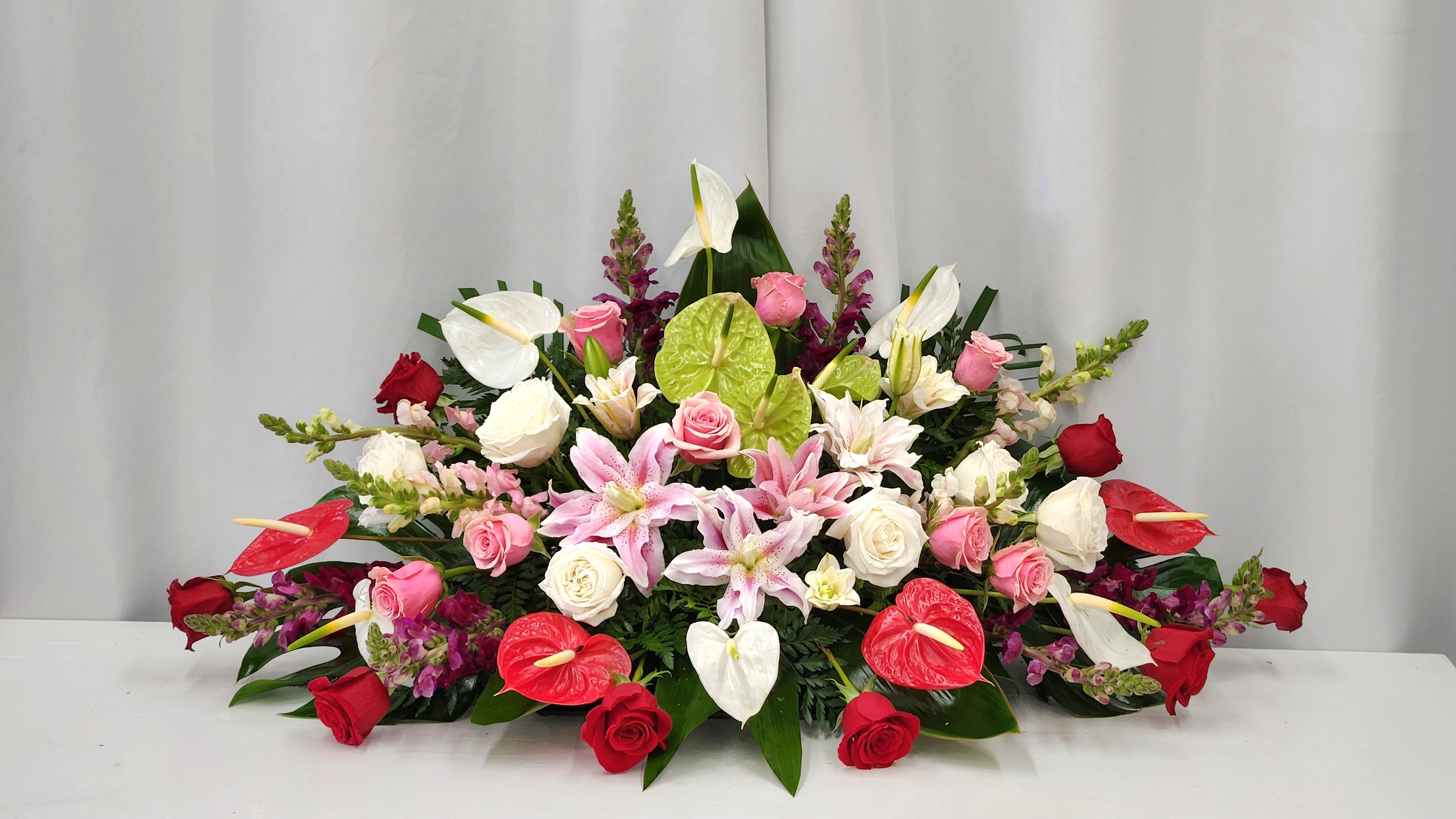 Tropical Garden Spray - The Tropical Garden Casket Spray is a strong and unique tribute that honors a life remembered with love. Its vibrant, exotic blooms create a powerful expression of admiration and comfort, offering a heartfelt way to celebrate a truly special individual. This arrangement brings both strength and beauty to moments of remembrance, providing solace and lasting connection. Premium - As Pictured: 52&quot;L X 30&quot;D 