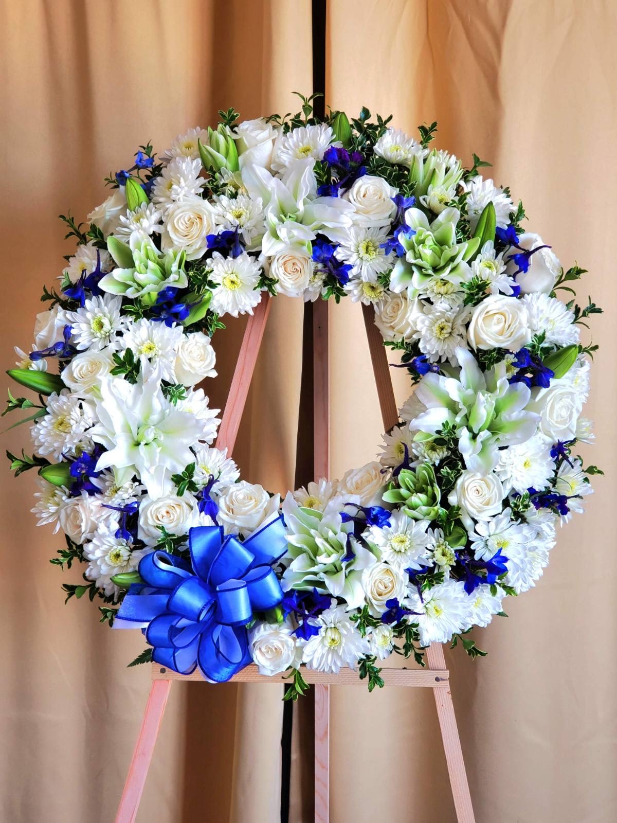 Blue Breeze Wreath - The white and blue wreath is elegant and beautiful, perfect for adding a touch of sophistication to any space. Thoughtfully designed with premium blooms in crisp whites and serene blues, this arrangement brings calm and comfort to grieving friends and families.  AS PICTTURED: PREMIUM 30&quot;