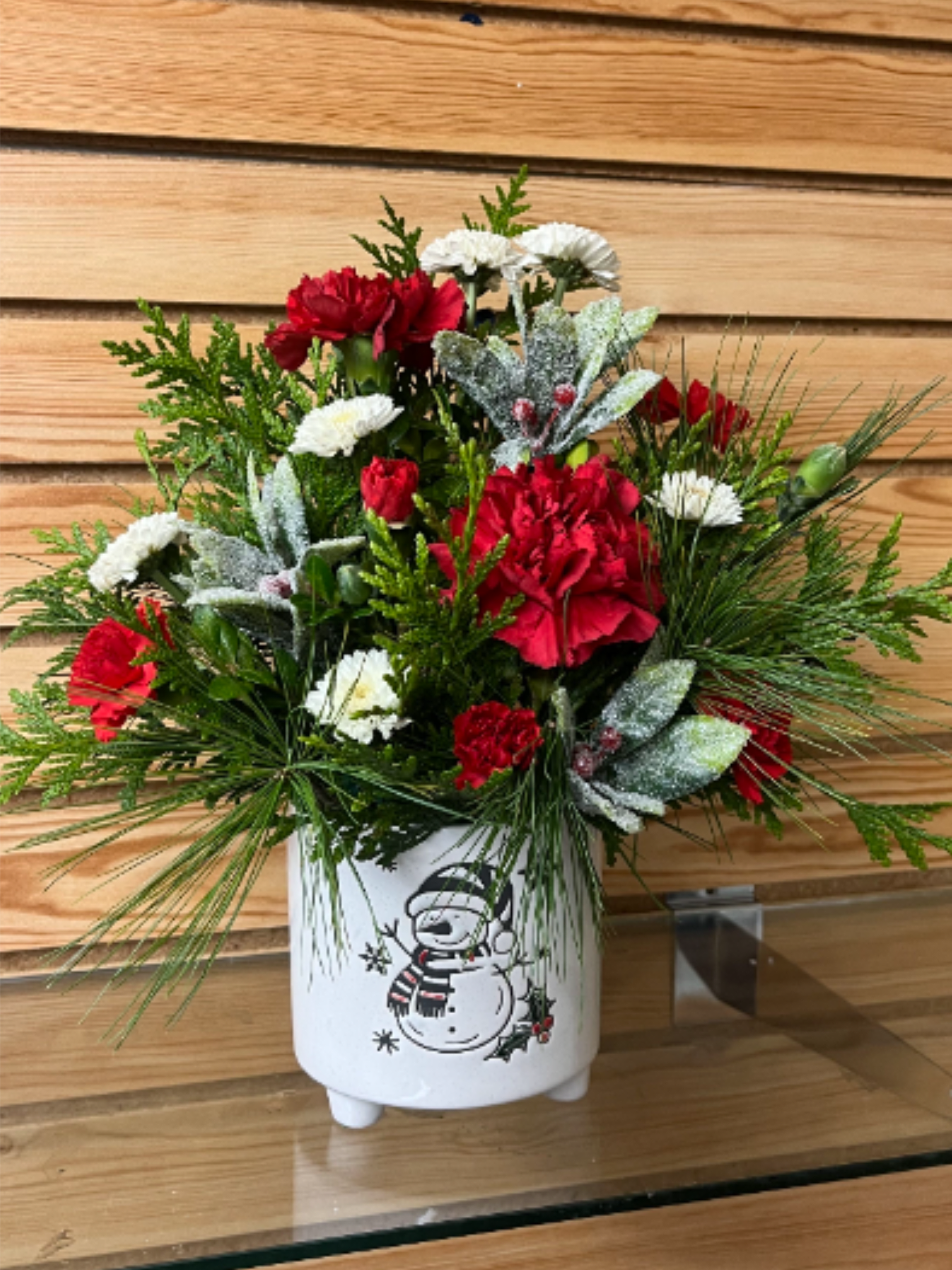 Frosty Wishes - With frosty berries and a happy snowman, this arrangement is the perfect wintery gift! It includes long lasting carnations and chrysanthemums and winter greens. Flowers may vary based on availability. 